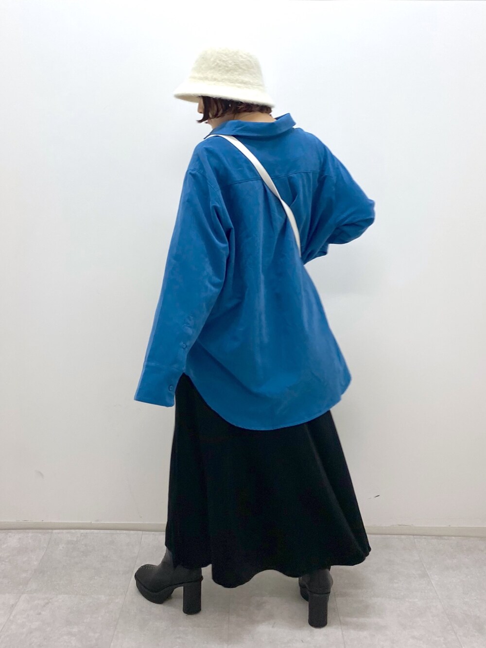 ブラック系のスカート、ホワイト系のバッグ、ブラック系のブーツを着用したレディースの秋コーディネートの3枚目の写真