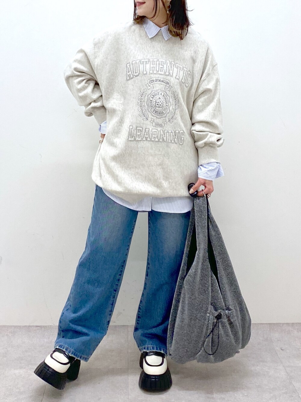 ベージュ系のスウェット、ブルー系のデニムパンツ、ブラック系のトートバッグを着用したレディースの冬コーディネートの3枚目の写真