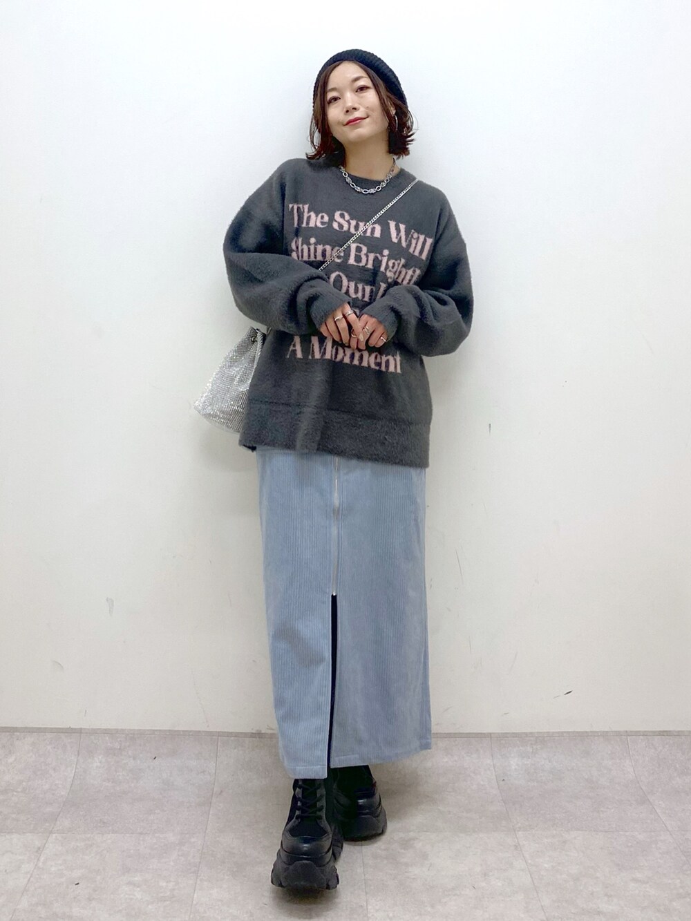 グレー系のニット/セーター、ブルー系のスカート、ブラック系のブーツを着用したレディースの秋コーディネートの4枚目の写真