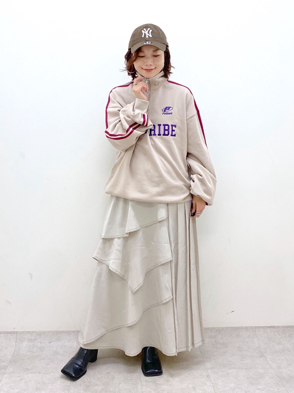 ベージュ系のスウェット、グレー系のスカート、ブラック系のブーツを着用したレディースの秋コーディネートの9枚目の写真