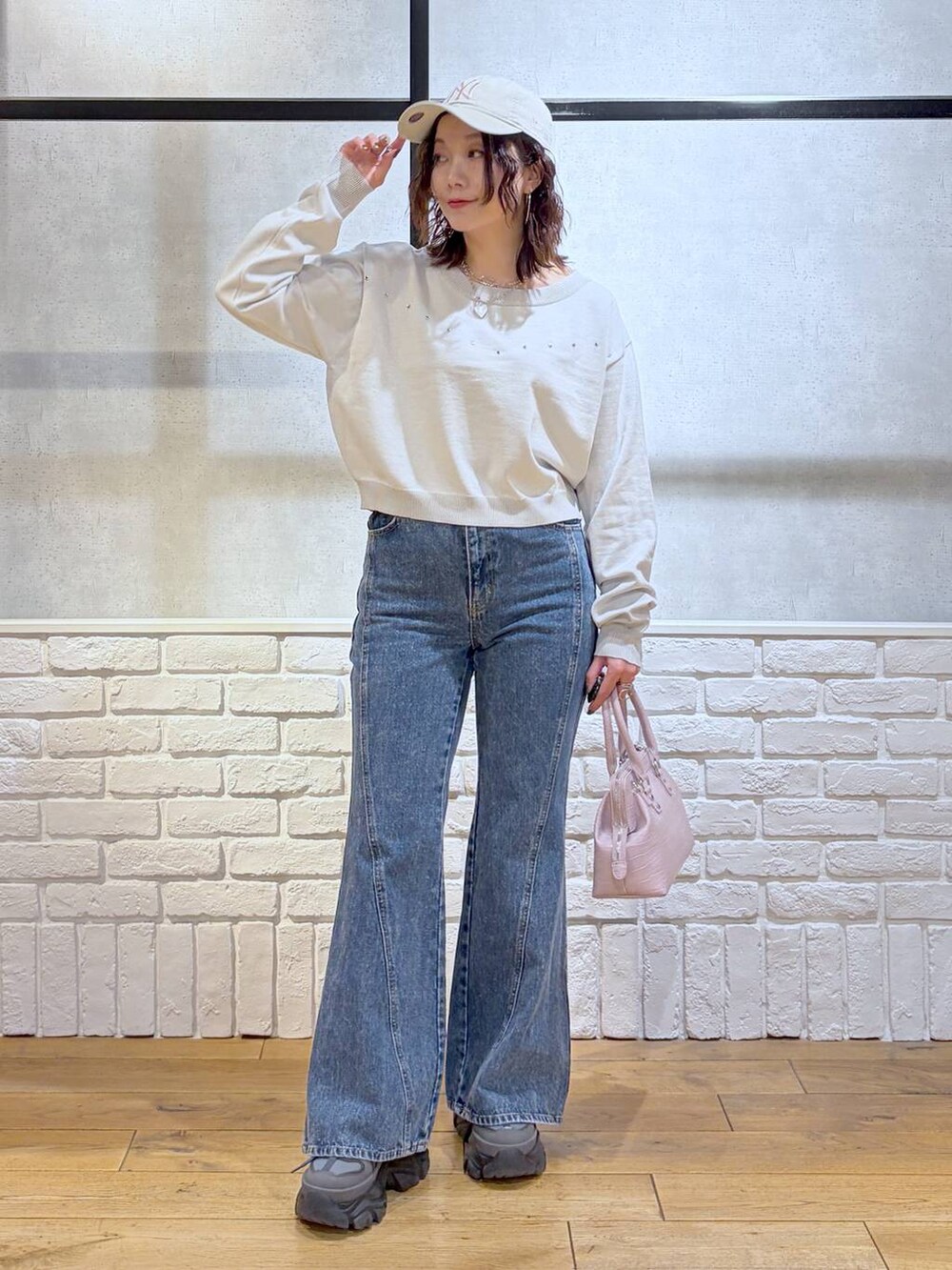グレー系のスニーカー、ブルー系のデニムパンツ、ピンク系のハンドバッグを着用したレディースの冬コーディネートの4枚目の写真