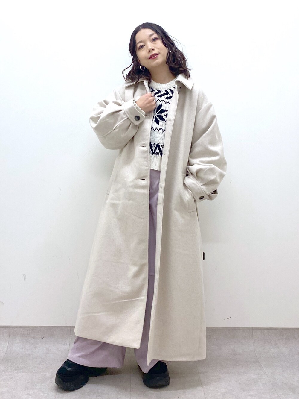 グレー系のチェスターコート、ホワイト系のニット/セーター、ピンク系のカーゴパンツを着用したレディースの冬コーディネートの2枚目の写真