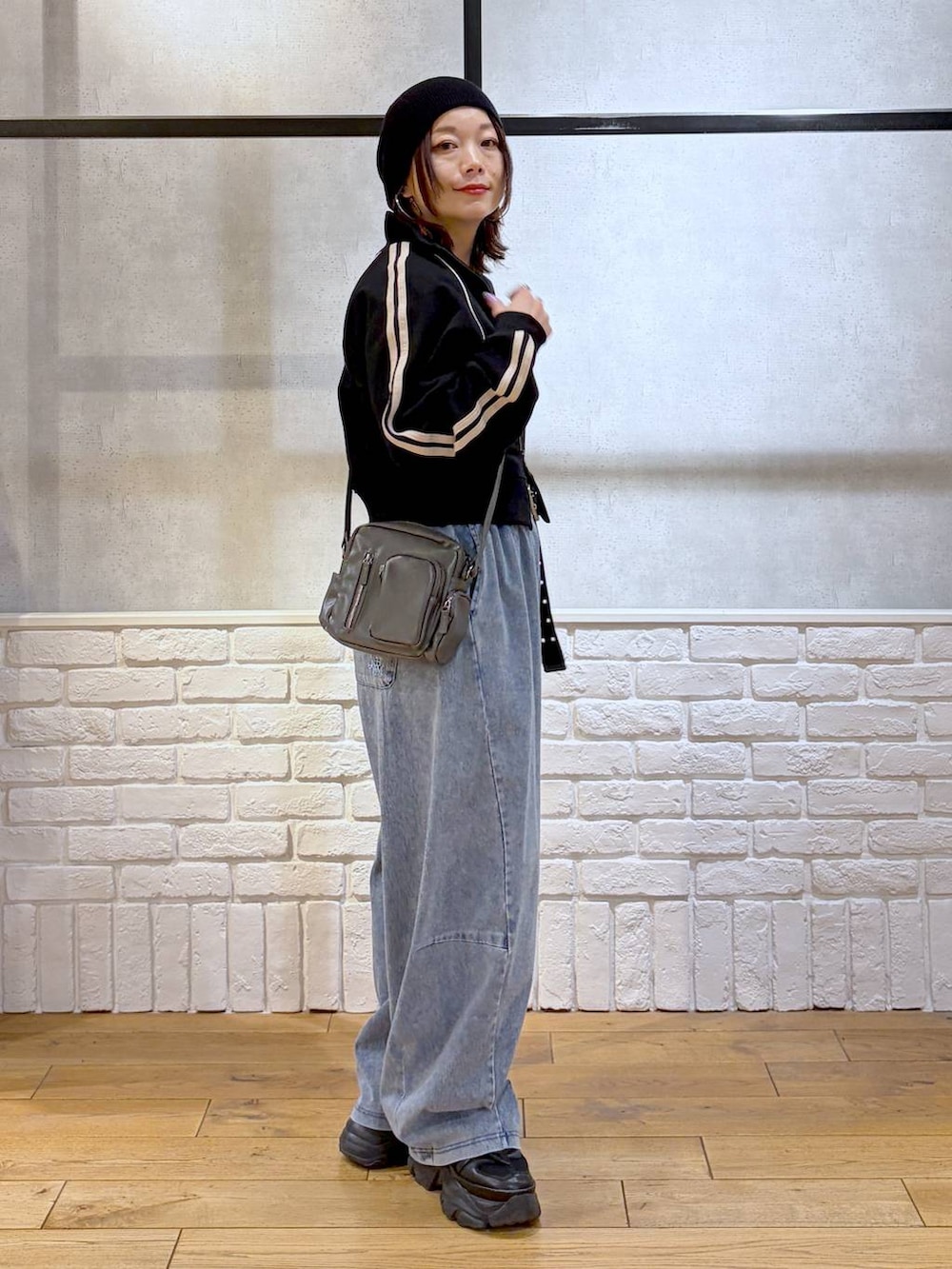 ブラック系のスニーカー、グレー系のショルダーバッグ、ブルー系のデニムパンツを着用したレディースの春コーディネートの5枚目の写真