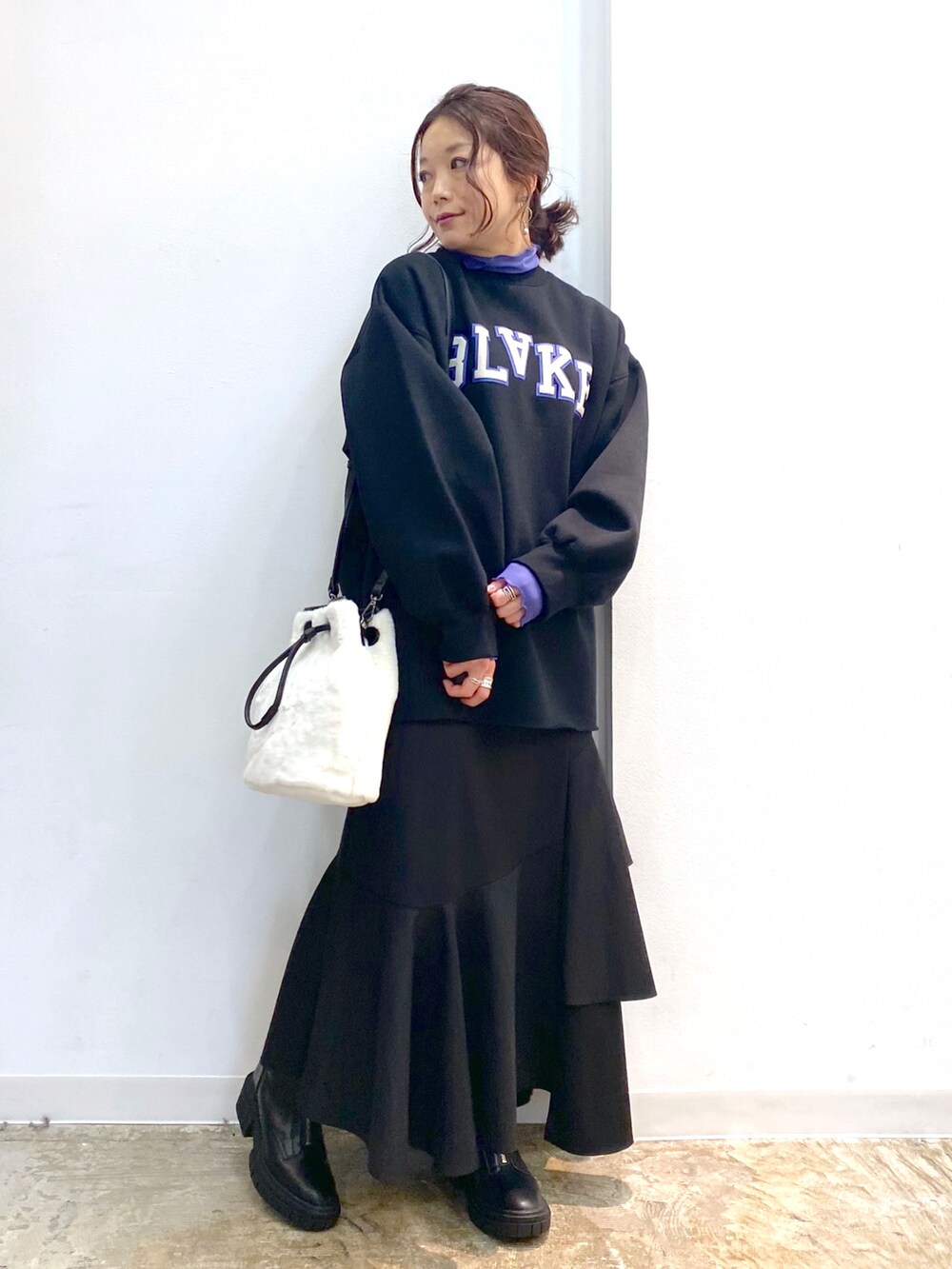 ブラック系のスカート、ブラック系のブーツ、ホワイト系のショルダーバッグを着用したレディースの秋コーディネートの4枚目の写真