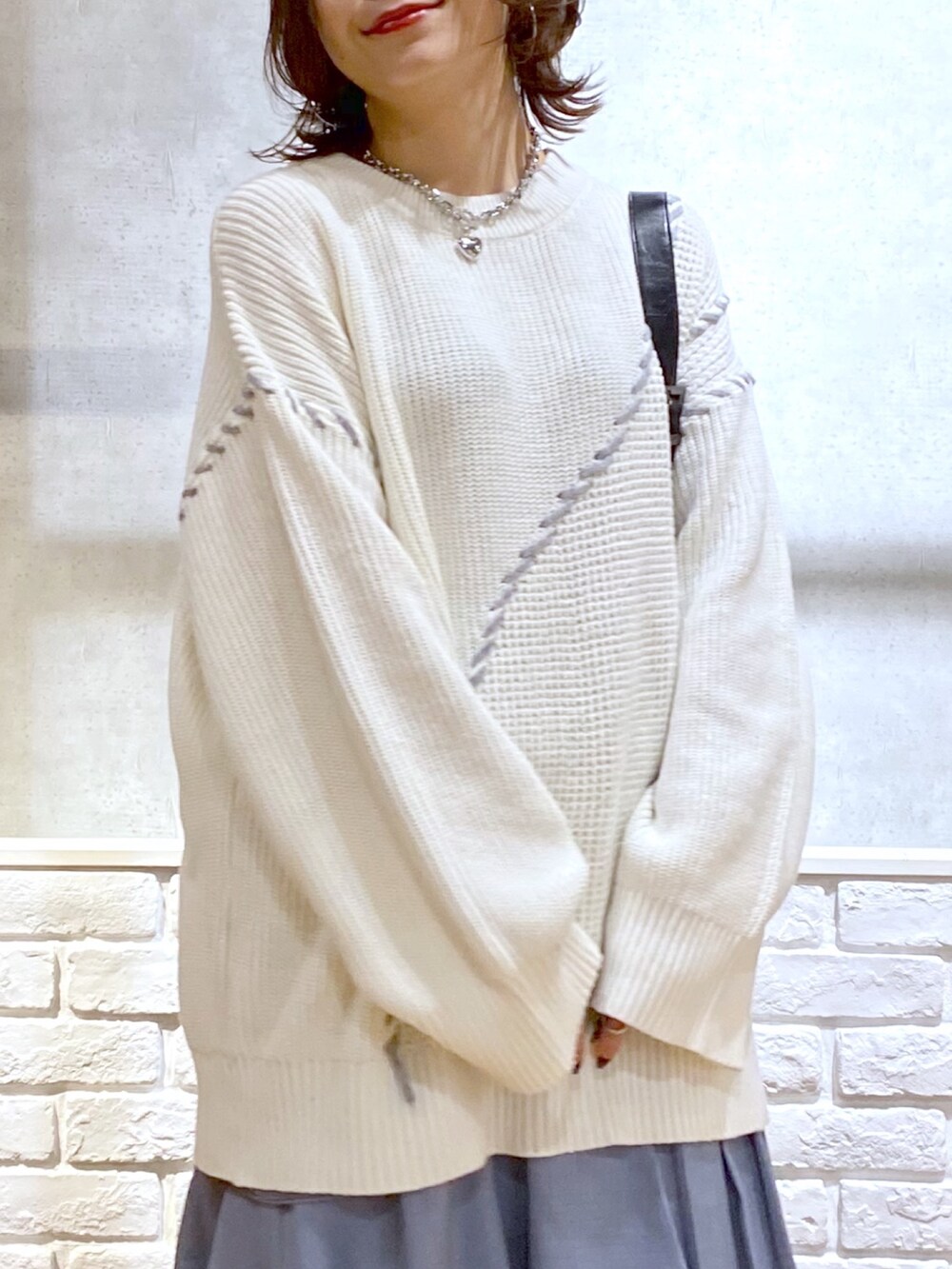 ホワイト系のニット/セーター、ブルー系のスカート、ブラック系のブーツを着用したレディースの冬コーディネートの2枚目の写真