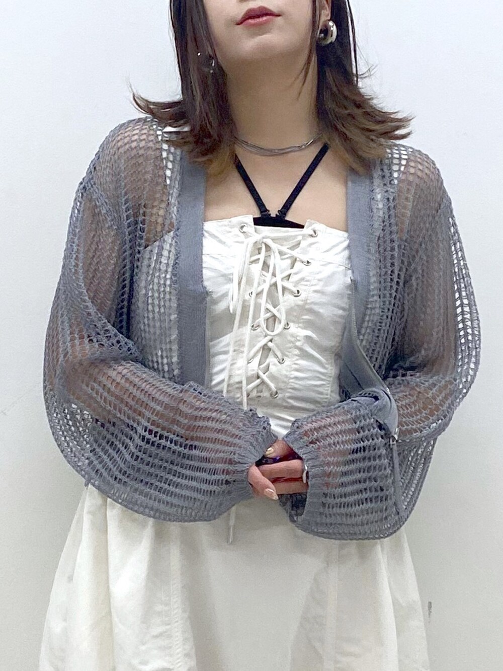 ホワイト系のワンピース、グレー系のカーディガン/ボレロ、ブラック系のサンダルを着用したレディースの春コーディネートの2枚目の写真