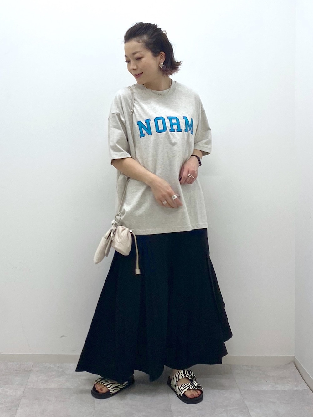 ベージュ系のTシャツ/カットソー、ブラック系のスカート、その他のサンダルを着用したレディースの夏コーディネートの2枚目の写真