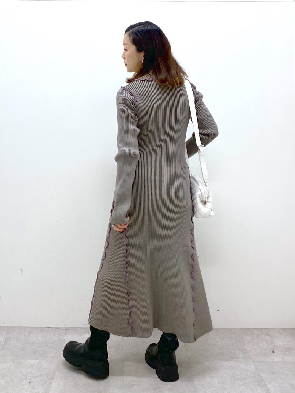 ブラウン系のワンピース、ホワイト系のショルダーバッグ、ブラック系のブーツを着用したレディースの秋コーディネートの5枚目の写真