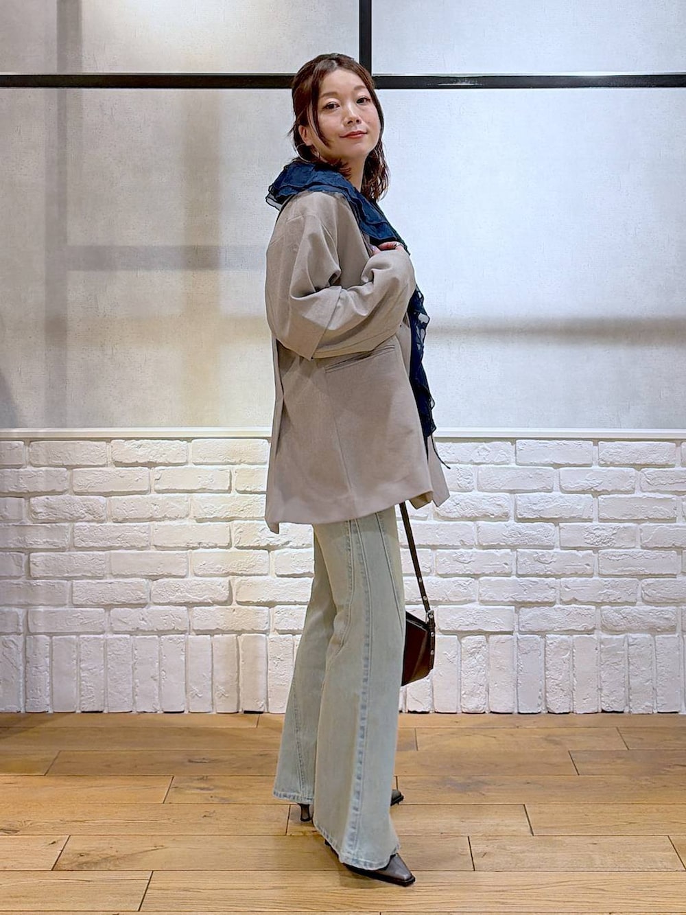 ブラック系のキャミソール、ブルー系のデニムパンツ、ブラウン系のハンドバッグを着用したレディースの春コーディネートの7枚目の写真