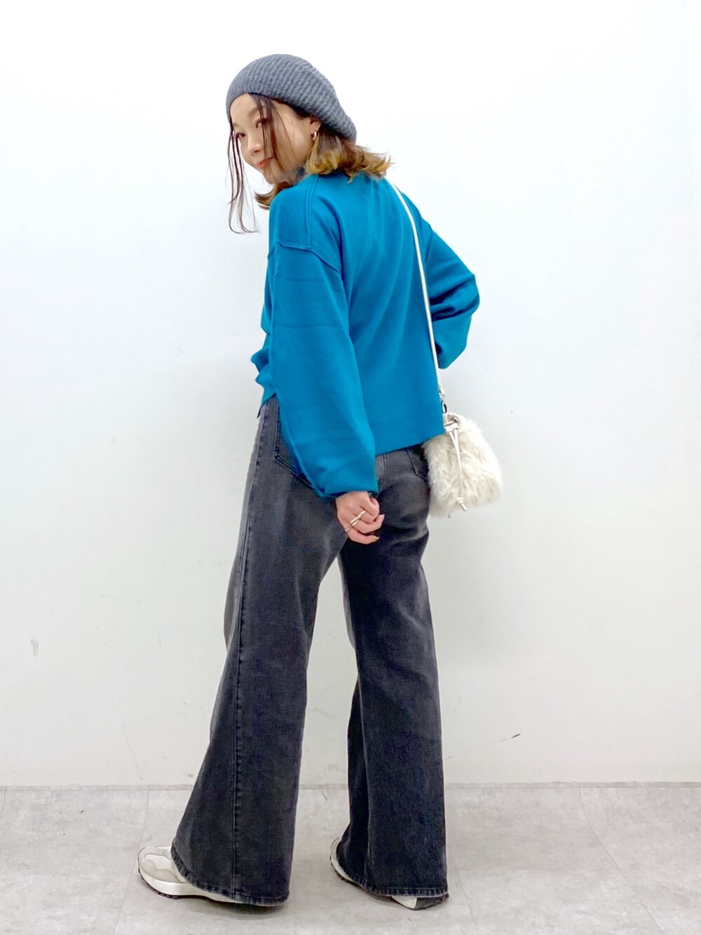 ブラック系のデニムパンツ、ホワイト系のショルダーバッグ、ブルー系のニット/セーターを着用したレディースの秋コーディネートの4枚目の写真