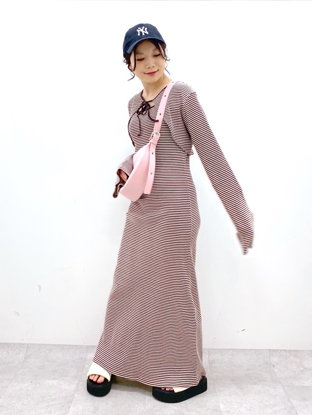 ブラウン系のワンピース、ピンク系のショルダーバッグ、ホワイト系のサンダルを着用したレディースの春コーディネートの2枚目の写真