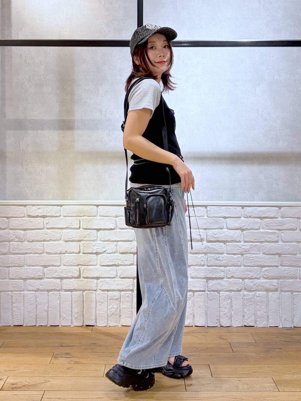 ブルー系のデニムパンツ、ブラック系のショルダーバッグ、ブラック系のサンダルを着用したレディースの春コーディネートの6枚目の写真