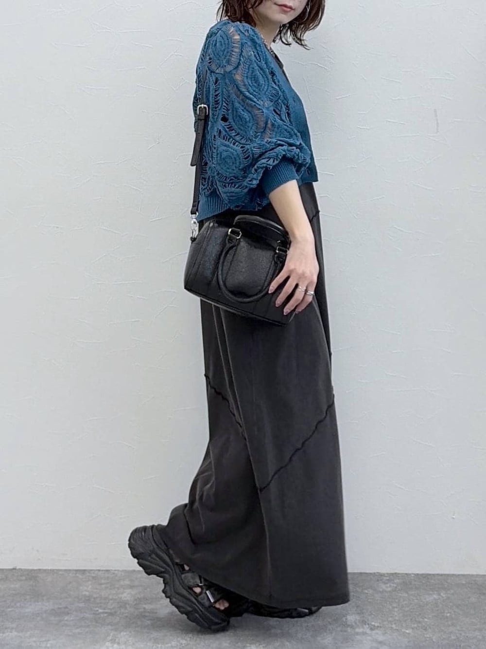 ブラック系のワンピース、ブルー系のカーディガン/ボレロ、ブラック系のボストンバッグを着用したレディースの春コーディネートの3枚目の写真