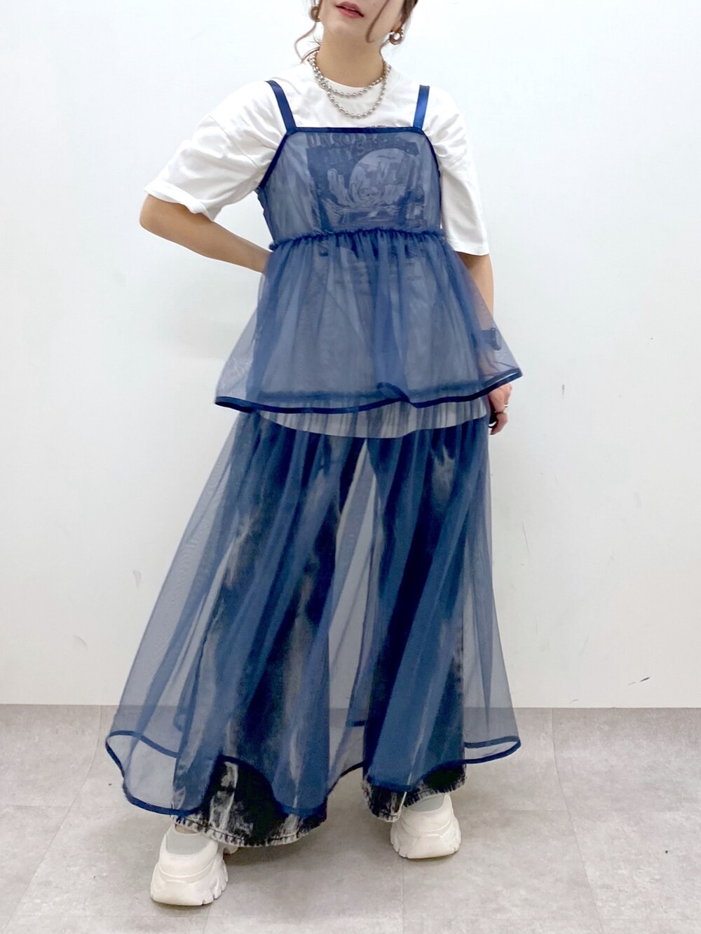 ホワイト系のTシャツ/カットソー、ブルー系のワンピース、ブラック系のデニムパンツを着用したレディースの春コーディネートの3枚目の写真