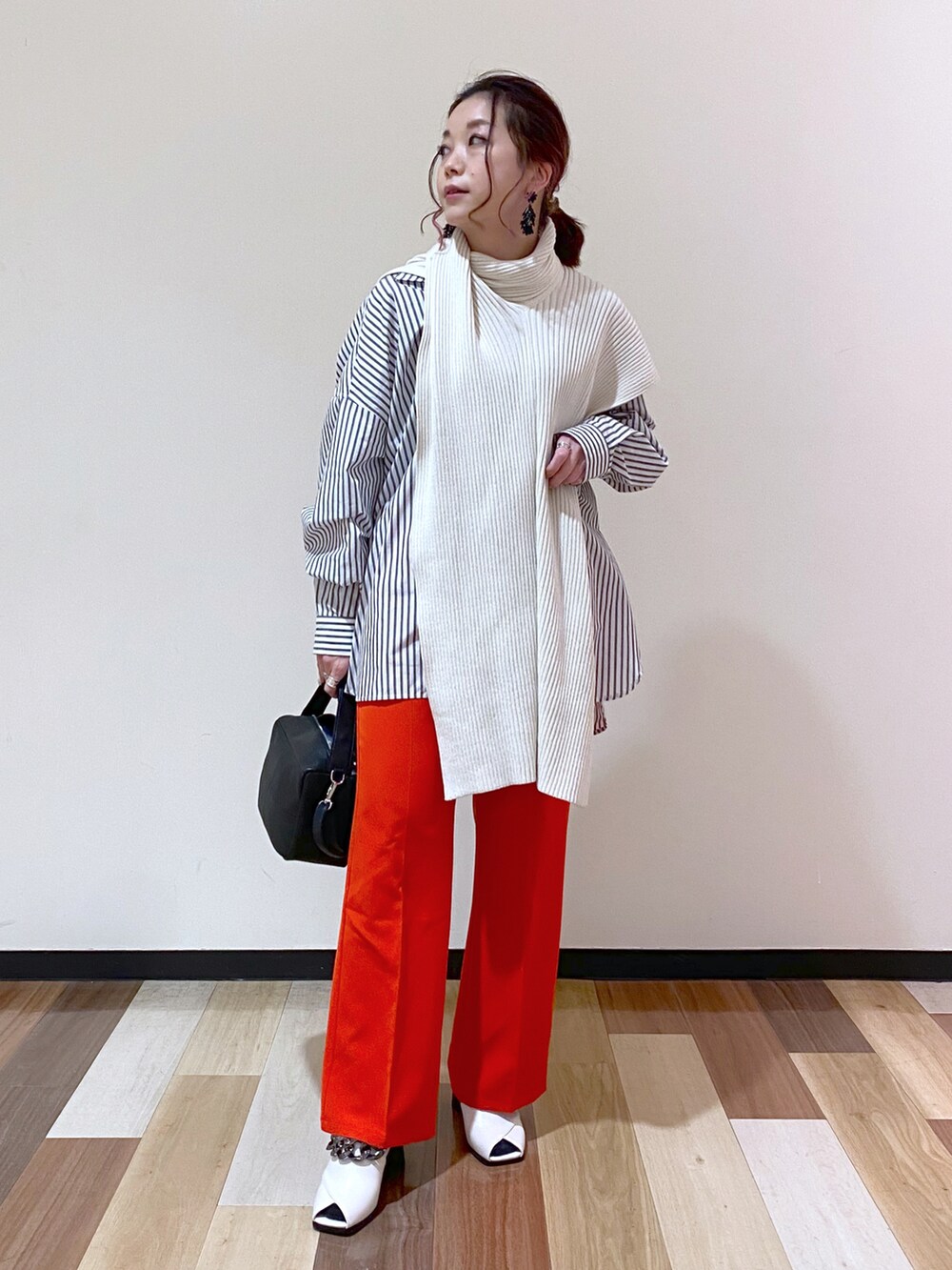 ブラック系のトレンチコート、レッド系のスラックス、ホワイト系のパンプスを着用したレディースの冬コーディネートの5枚目の写真