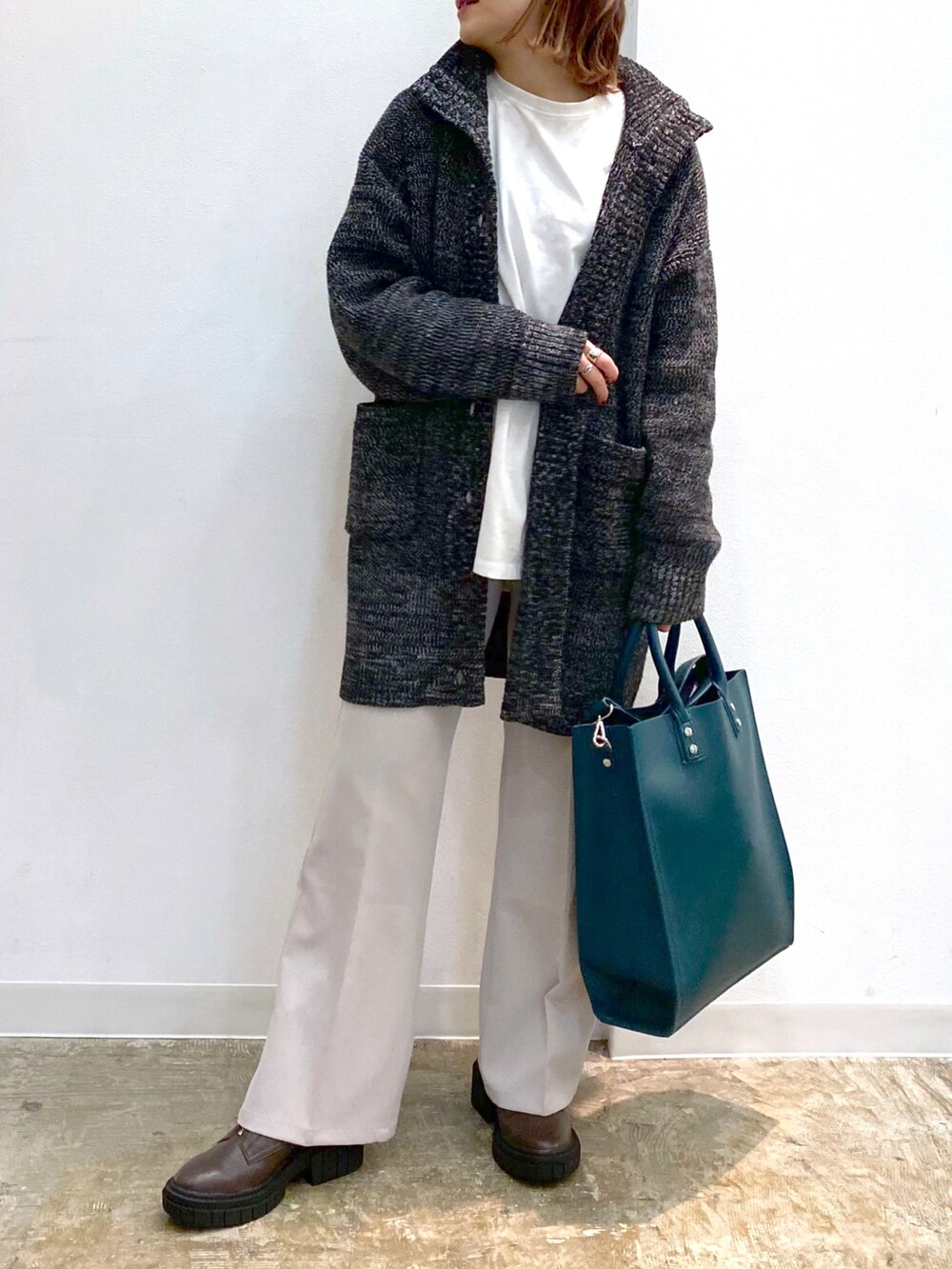 ホワイト系のTシャツ/カットソー、ブラック系のニット/セーター、グリーン系のトートバッグを着用したレディースの冬コーディネートの3枚目の写真