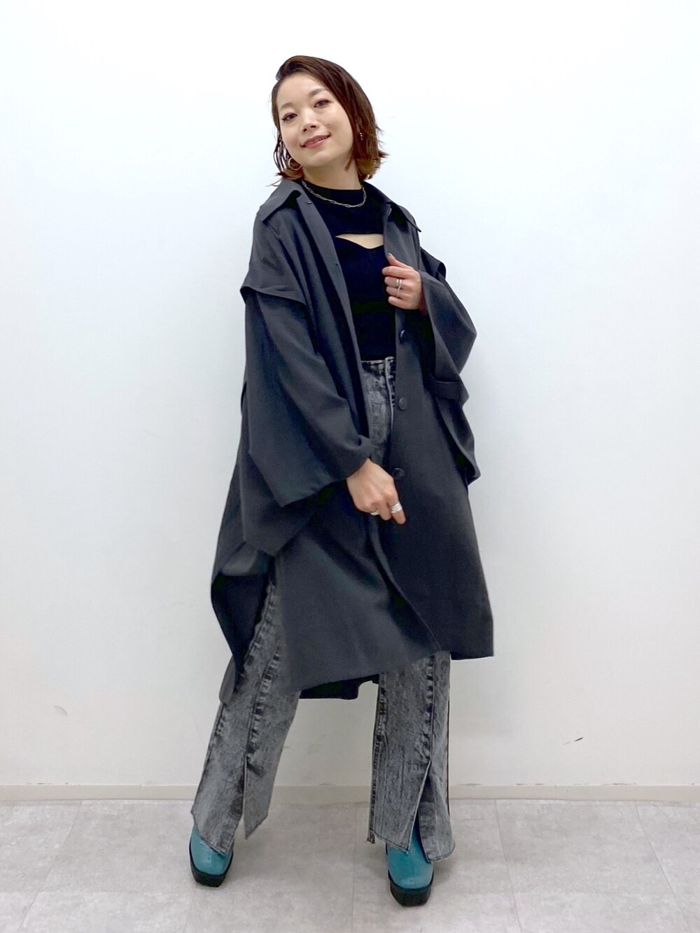 ブラック系のデニムパンツ、グレー系のポンチョ、ブラック系のトップスを着用したレディースの夏コーディネートの4枚目の写真