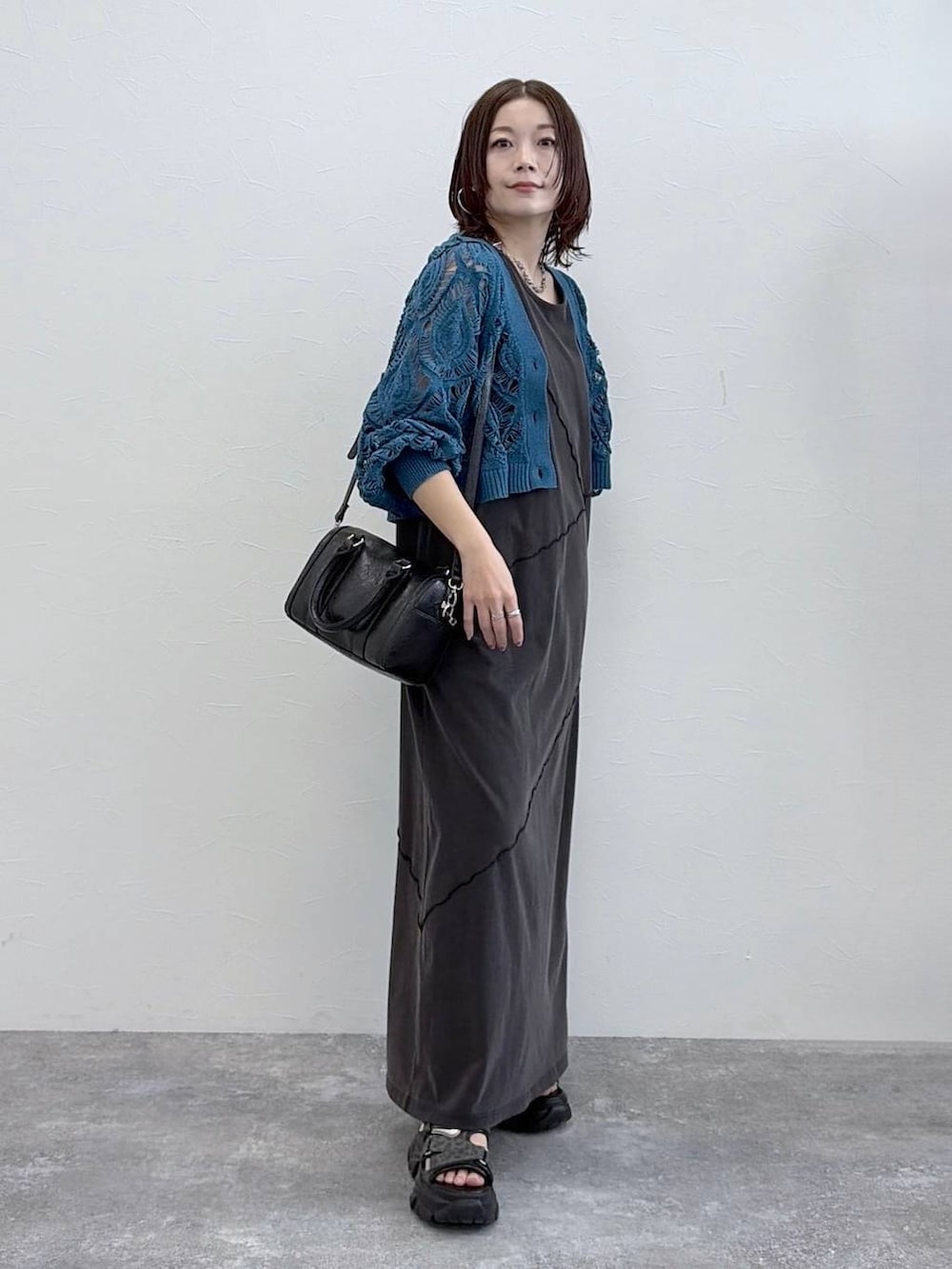 ブラック系のワンピース、ブルー系のカーディガン/ボレロ、ブラック系のボストンバッグを着用したレディースの春コーディネートの4枚目の写真