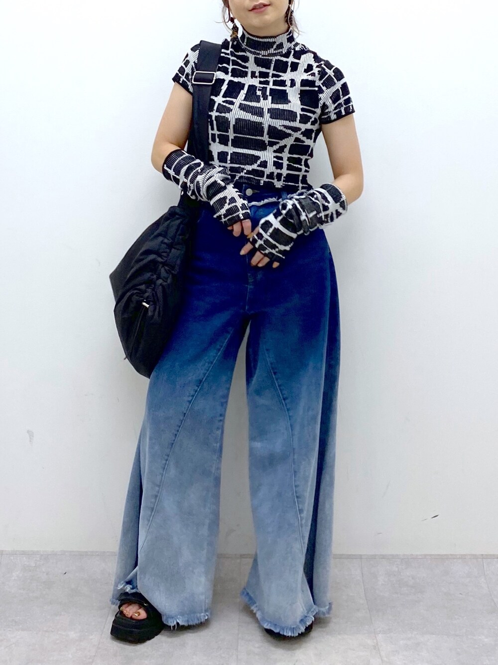 ブルー系のデニムパンツ、ブラック系のニット/セーター、ブラック系のショルダーバッグを着用したレディースの夏コーディネートの7枚目の写真