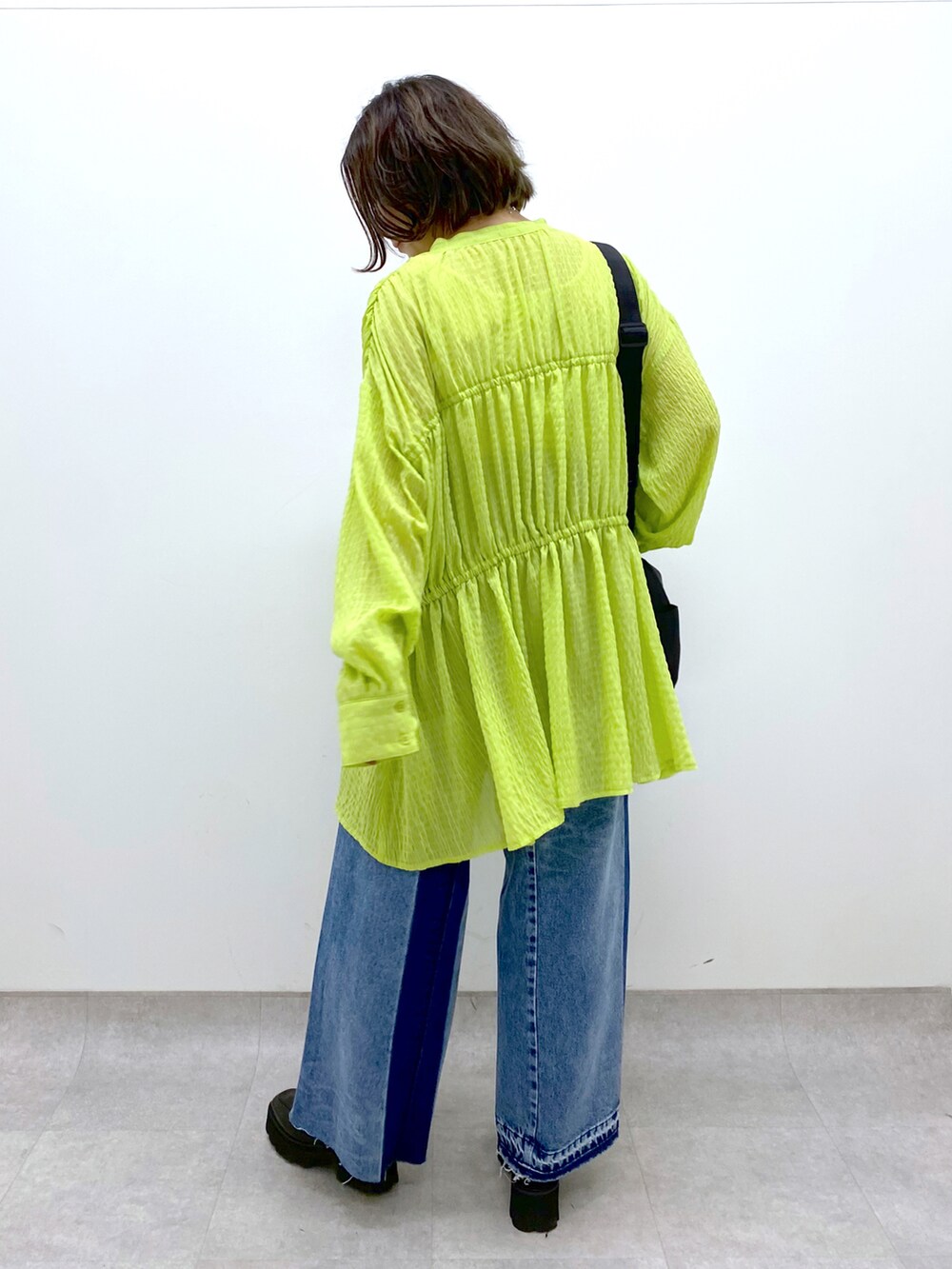 ブルー系のデニムパンツ、ホワイト系のトップス、イエロー系のトップスを着用したレディースの春コーディネートの3枚目の写真