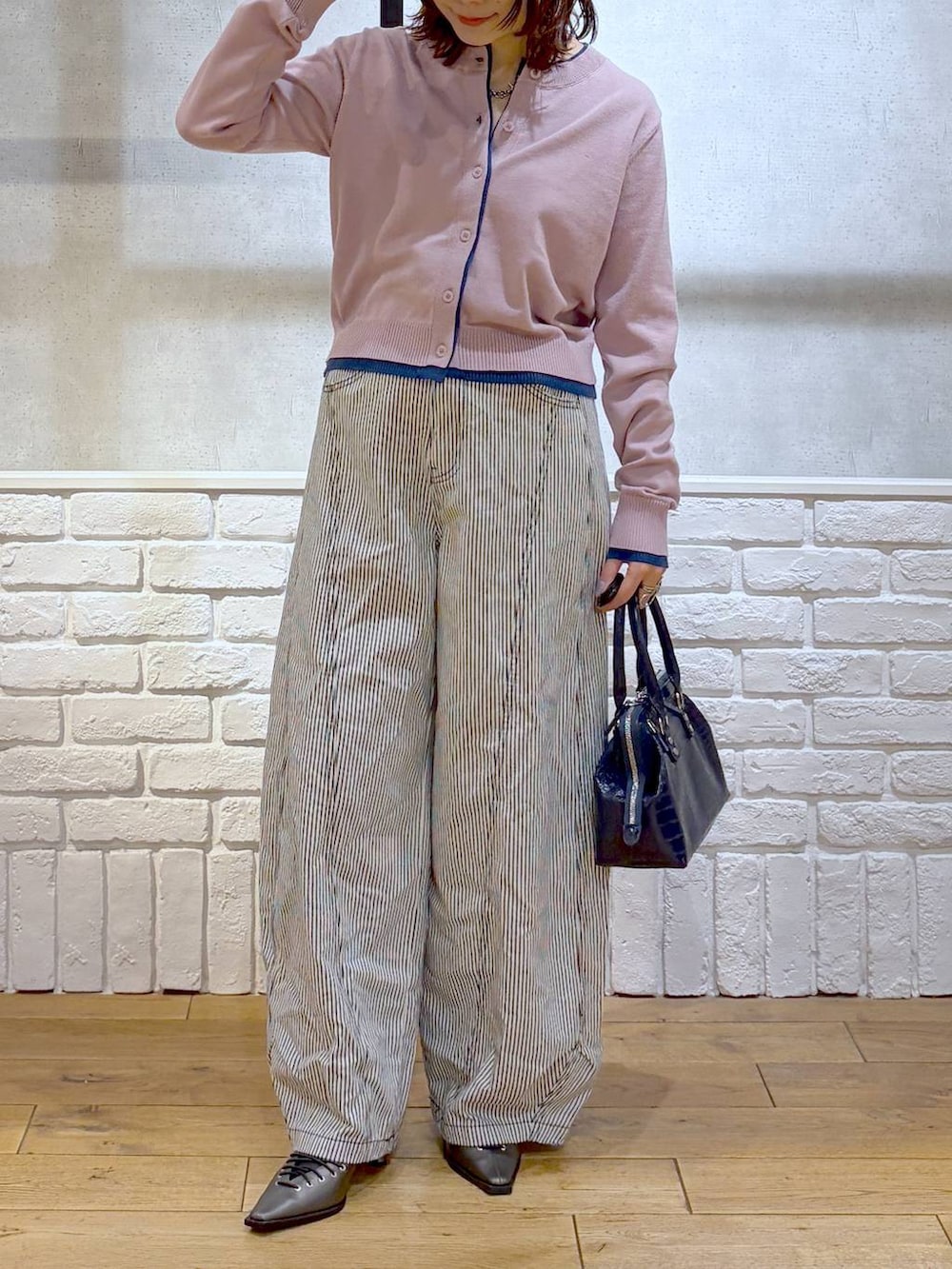 ブルー系のハンドバッグ、ブラウン系のサンダル、ブラック系のデニムパンツを着用したレディースの冬コーディネートの3枚目の写真