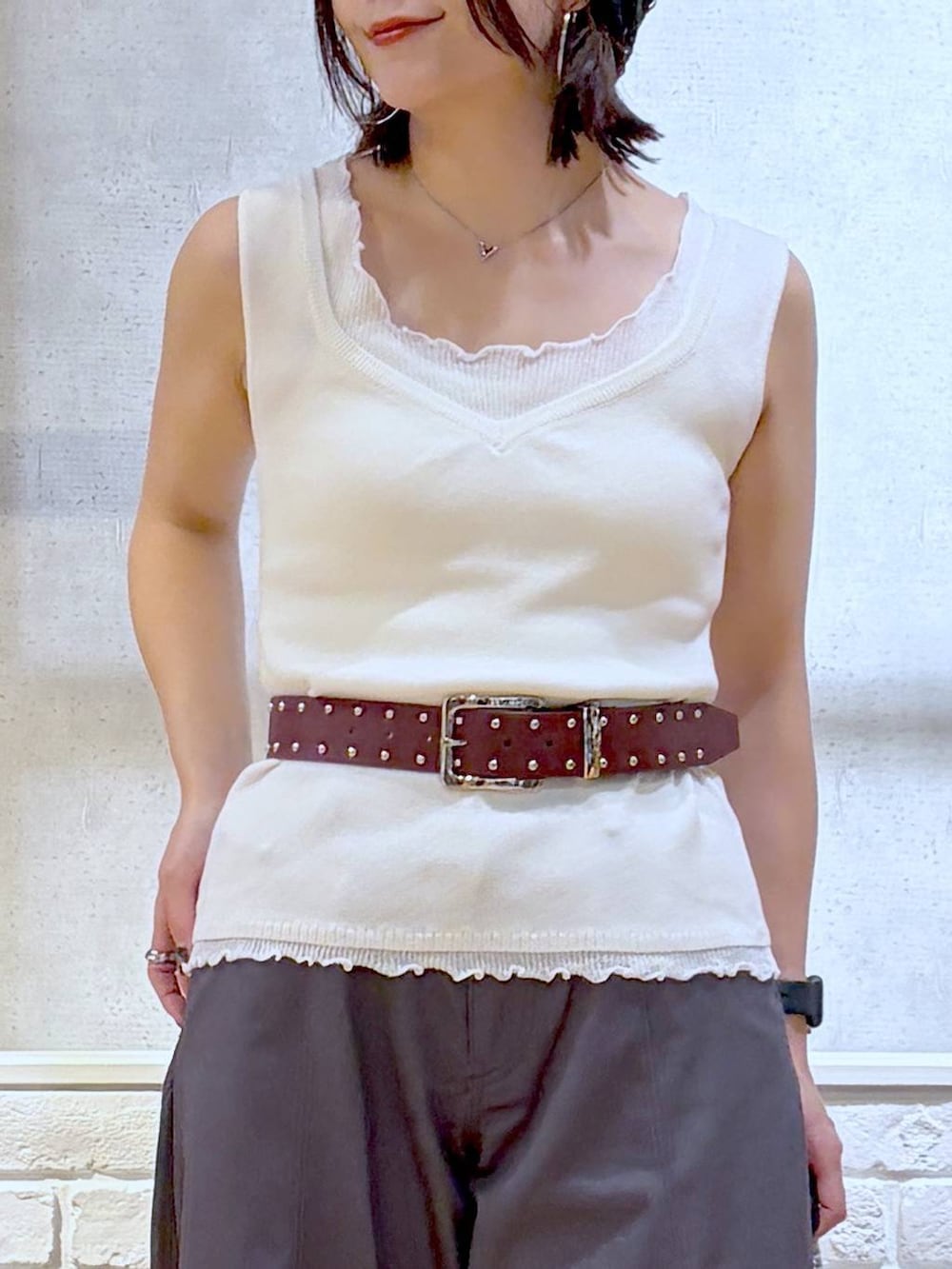 シルバー系のショルダーバッグ、ブラック系のサンダル、ホワイト系のタンクトップを着用したレディースの夏コーディネートの2枚目の写真