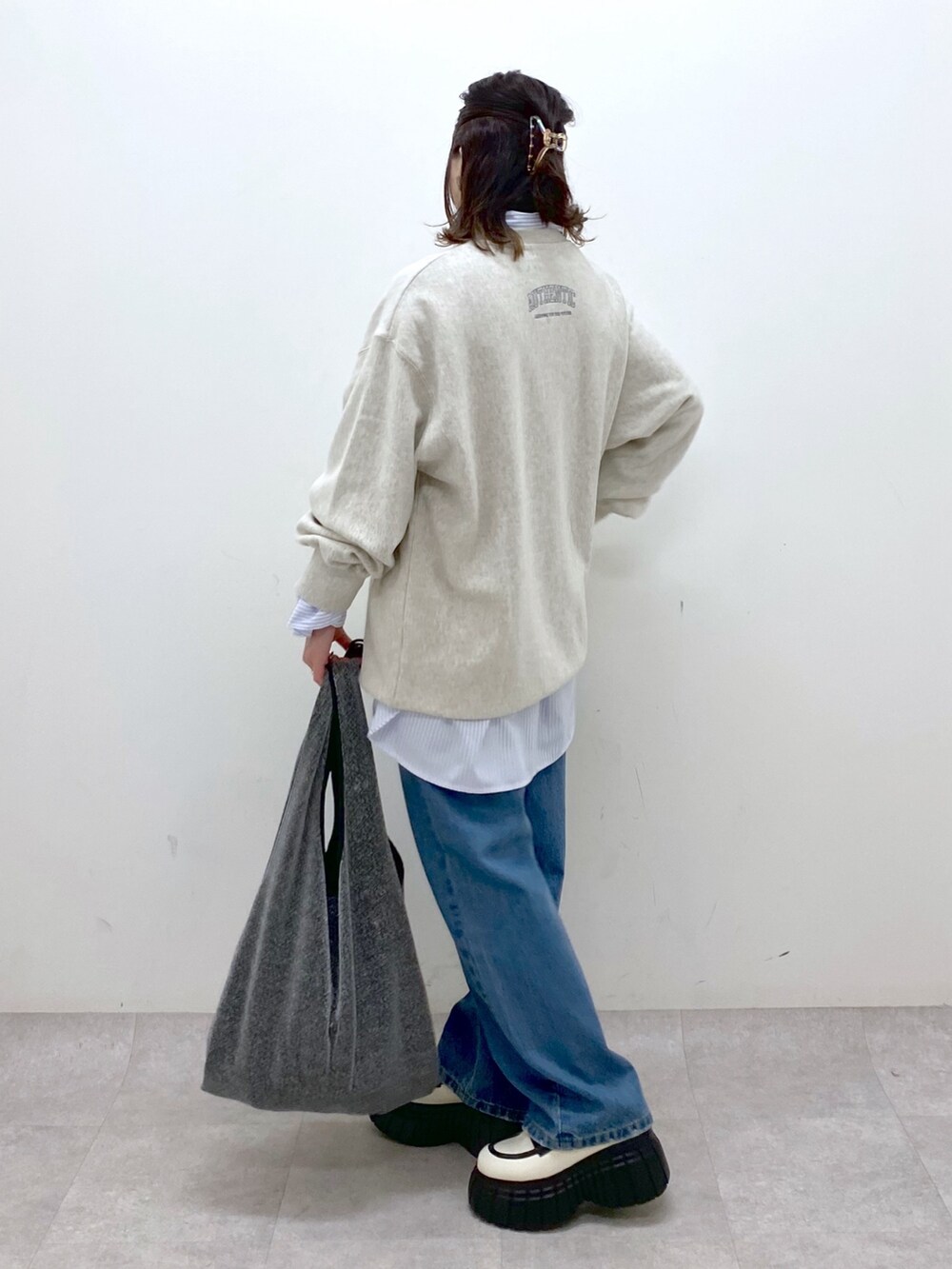 ベージュ系のスウェット、ブルー系のデニムパンツ、ブラック系のトートバッグを着用したレディースの冬コーディネートの7枚目の写真