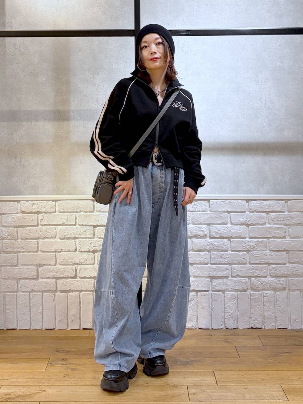 ブラック系のスニーカー、グレー系のショルダーバッグ、ブルー系のデニムパンツを着用したレディースの春コーディネートの4枚目の写真