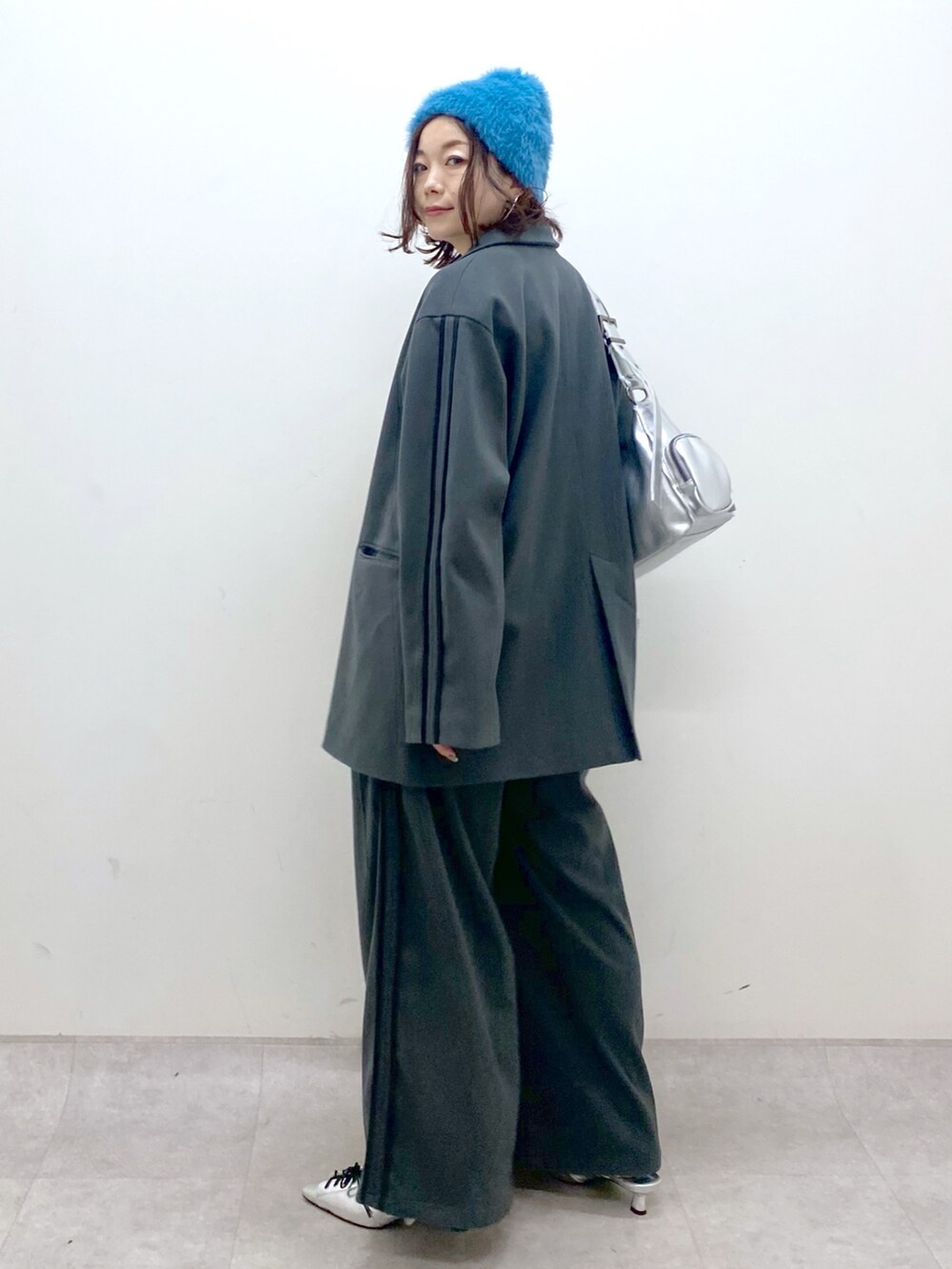 グレー系のスラックス、シルバー系のパンプス、シルバー系のショルダーバッグを着用したレディースの秋コーディネートの8枚目の写真