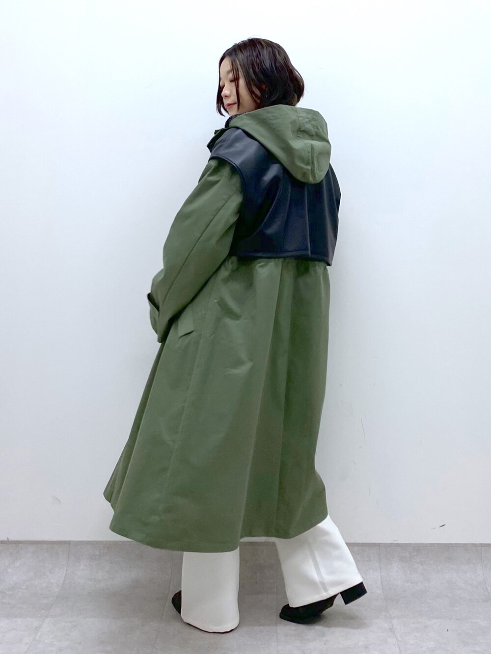 グリーン系のモッズコート、ホワイト系のスラックス、ブラック系のシューズを着用したレディースの冬コーディネートの2枚目の写真