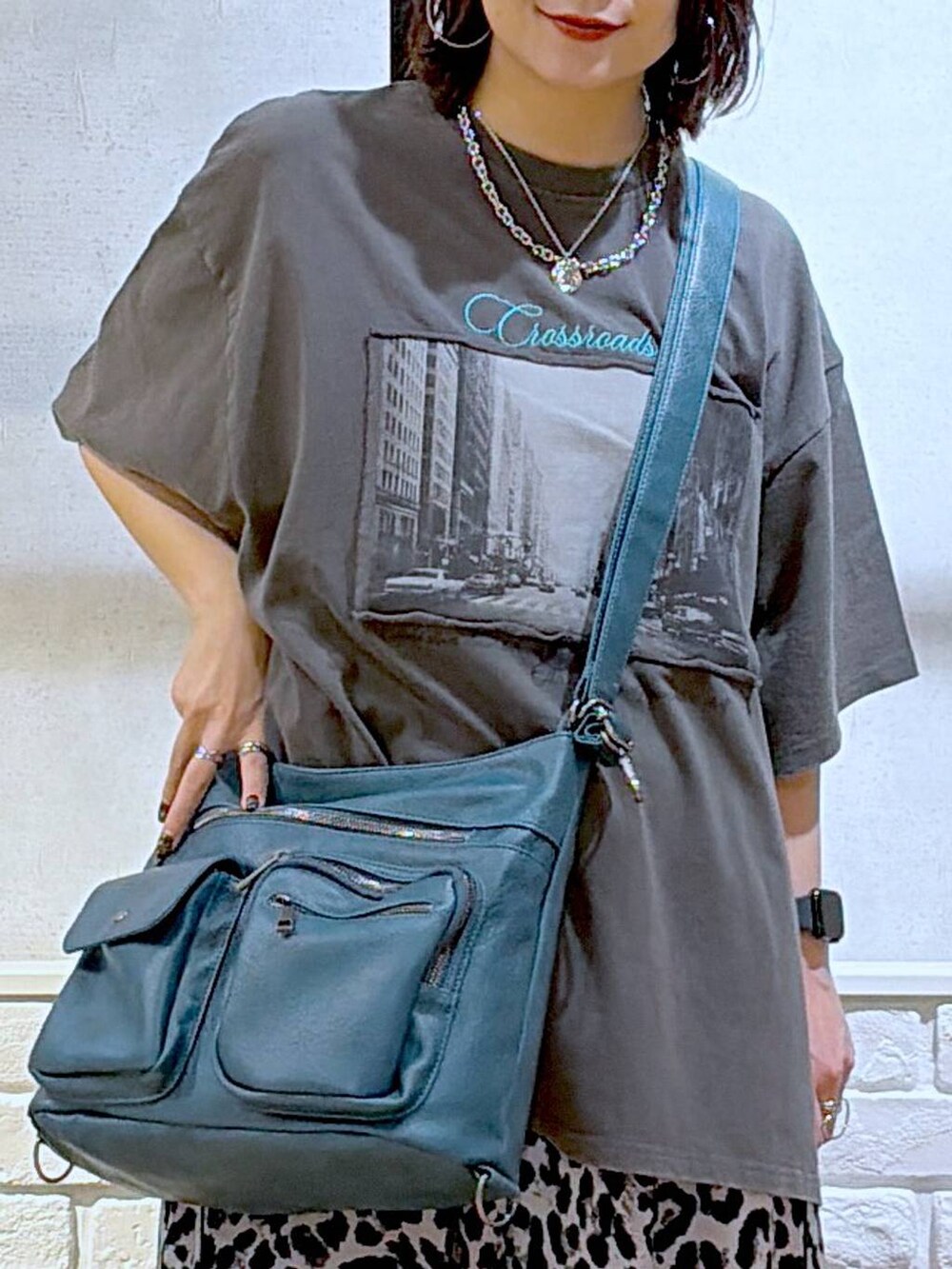 ブルー系のショルダーバッグ、ブラック系のサンダル、グレー系のスラックスを着用したレディースの春コーディネートの2枚目の写真