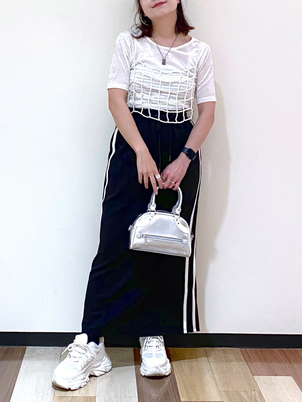 ブラック系のスカート、シルバー系のショルダーバッグ、ホワイト系のスニーカーを着用したレディースの夏コーディネートの3枚目の写真