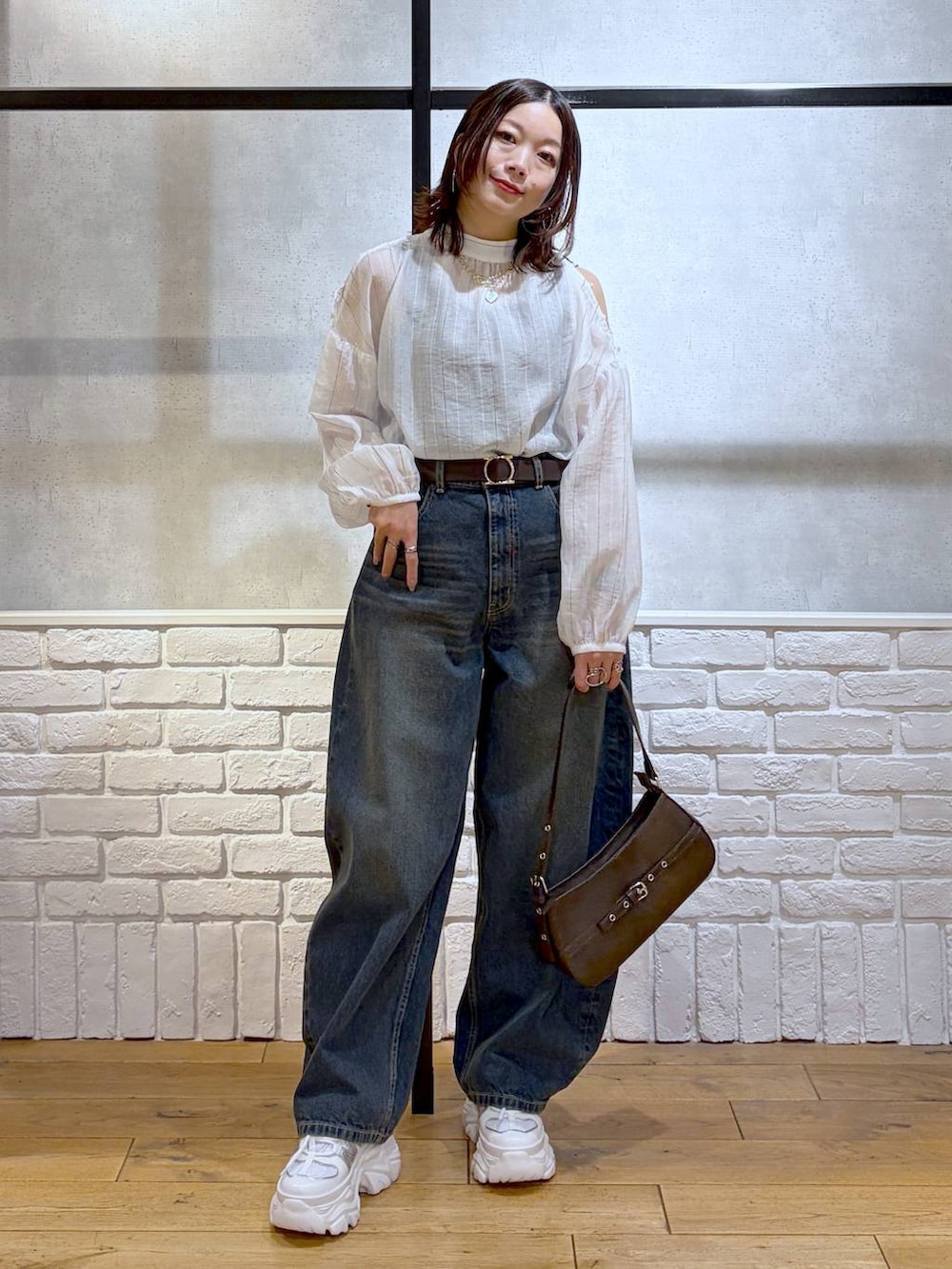 ホワイト系のスニーカー、ブルー系のデニムパンツ、ブラウン系のハンドバッグを着用したレディースの春コーディネートの9枚目の写真
