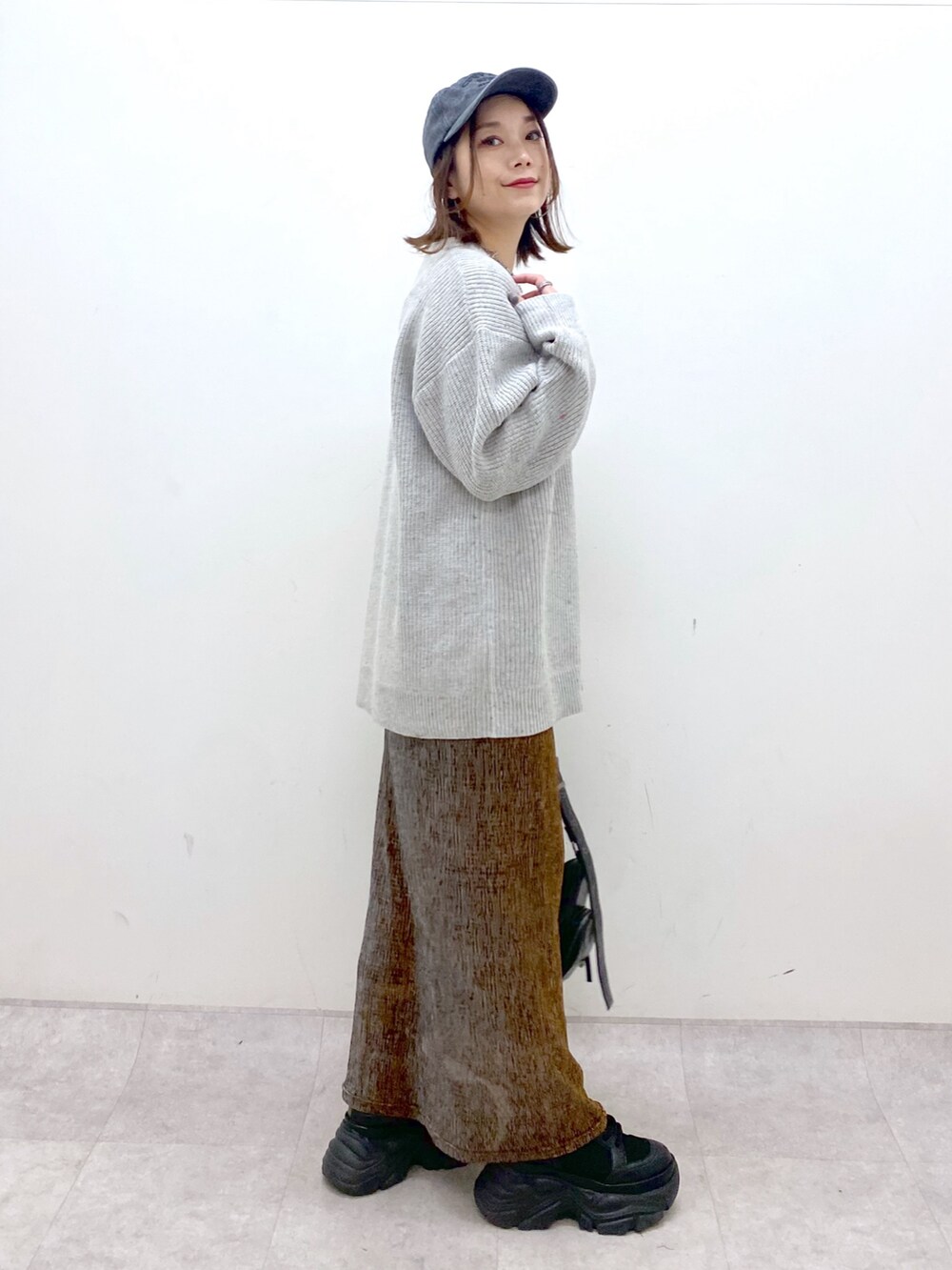 グレー系のニット/セーター、ゴールド系のスカート、ブラック系のショルダーバッグを着用したレディースの冬コーディネートの7枚目の写真