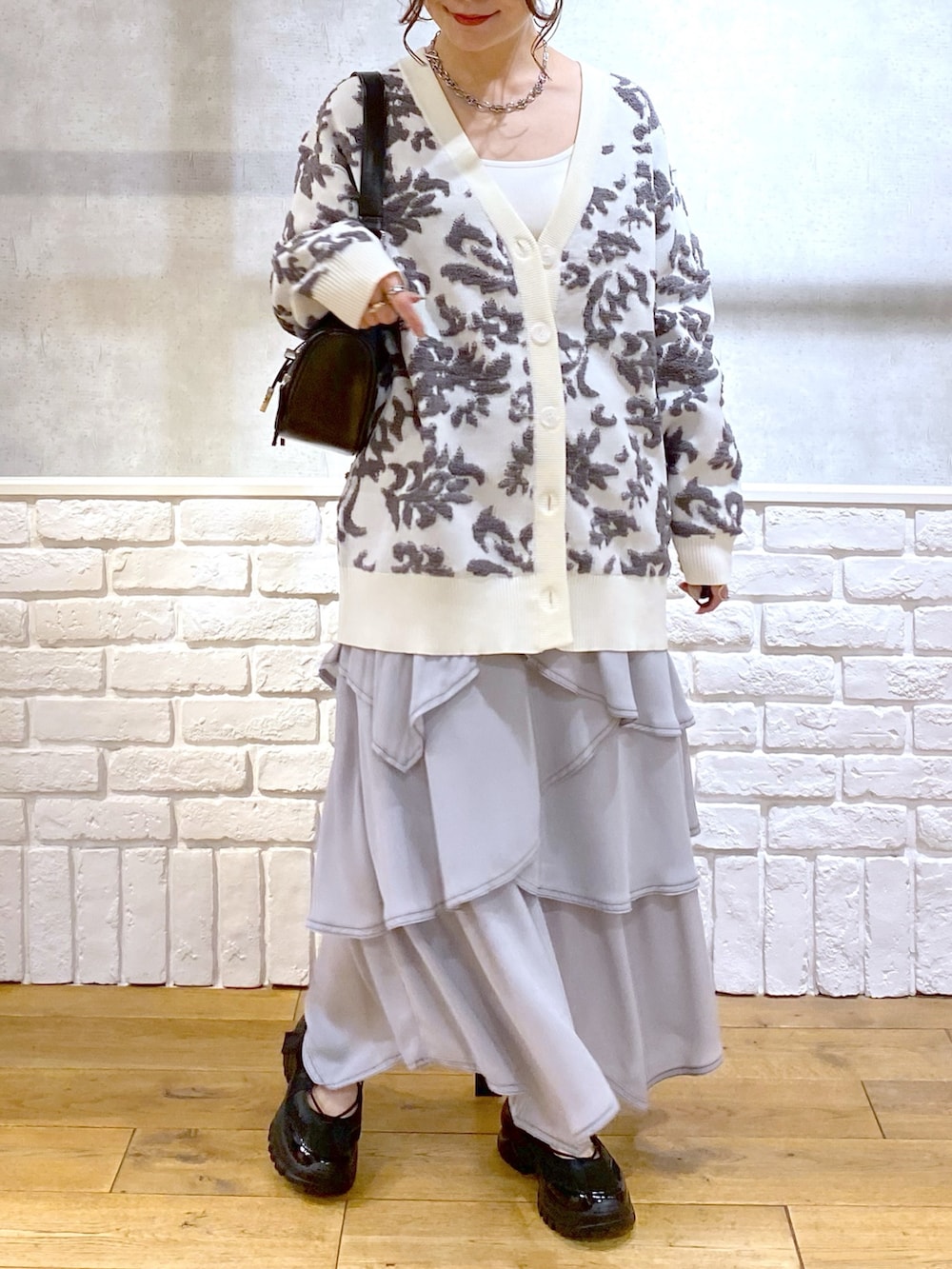 ブラック系のショルダーバッグ、ホワイト系のカーディガン/ボレロ、ホワイト系のキャミソールを着用したレディースの春コーディネートの3枚目の写真