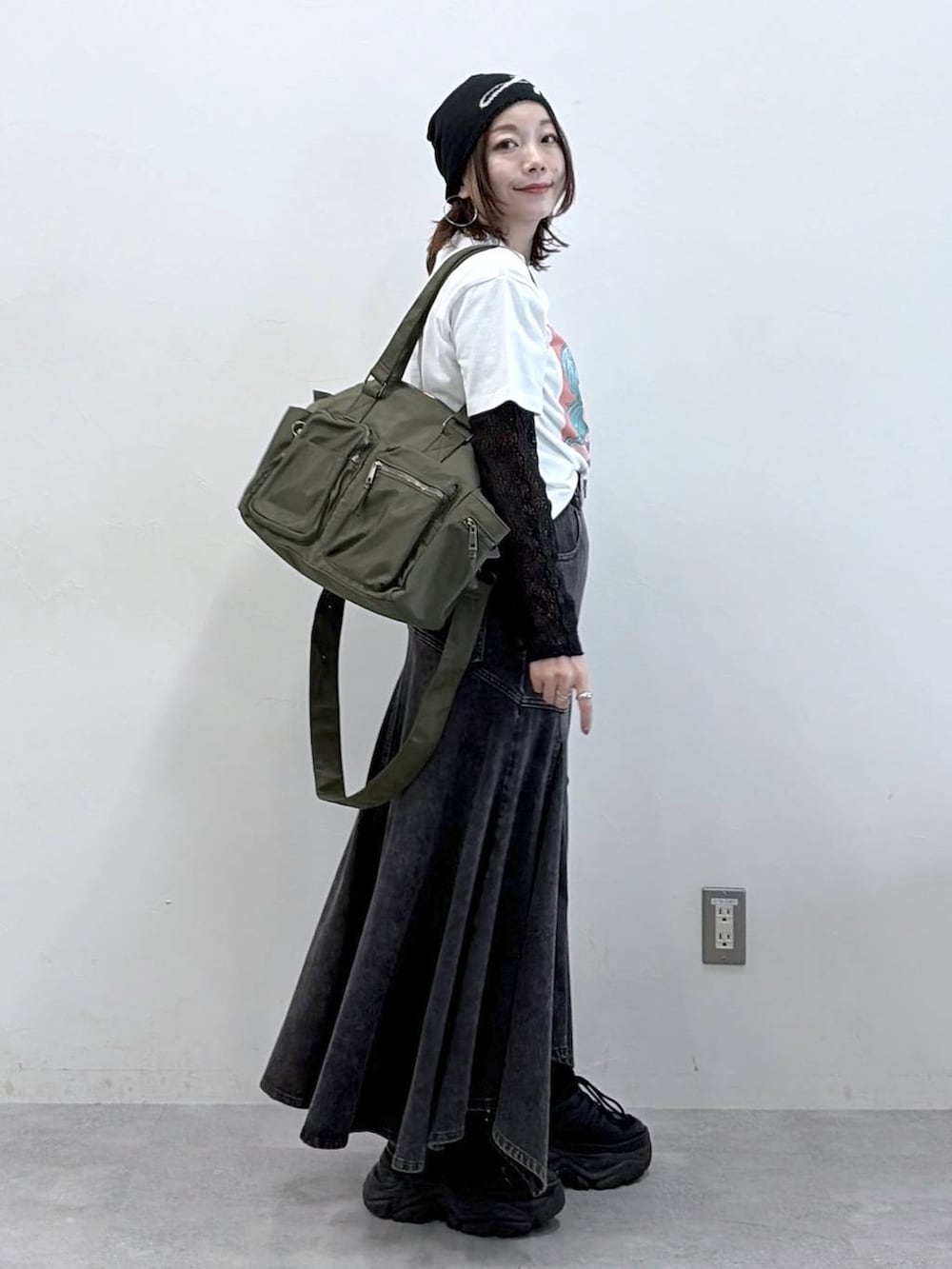 ブラック系のスニーカー、グリーン系のボストンバッグ、ブラック系のデニムスカートを着用したレディースの春コーディネートの4枚目の写真