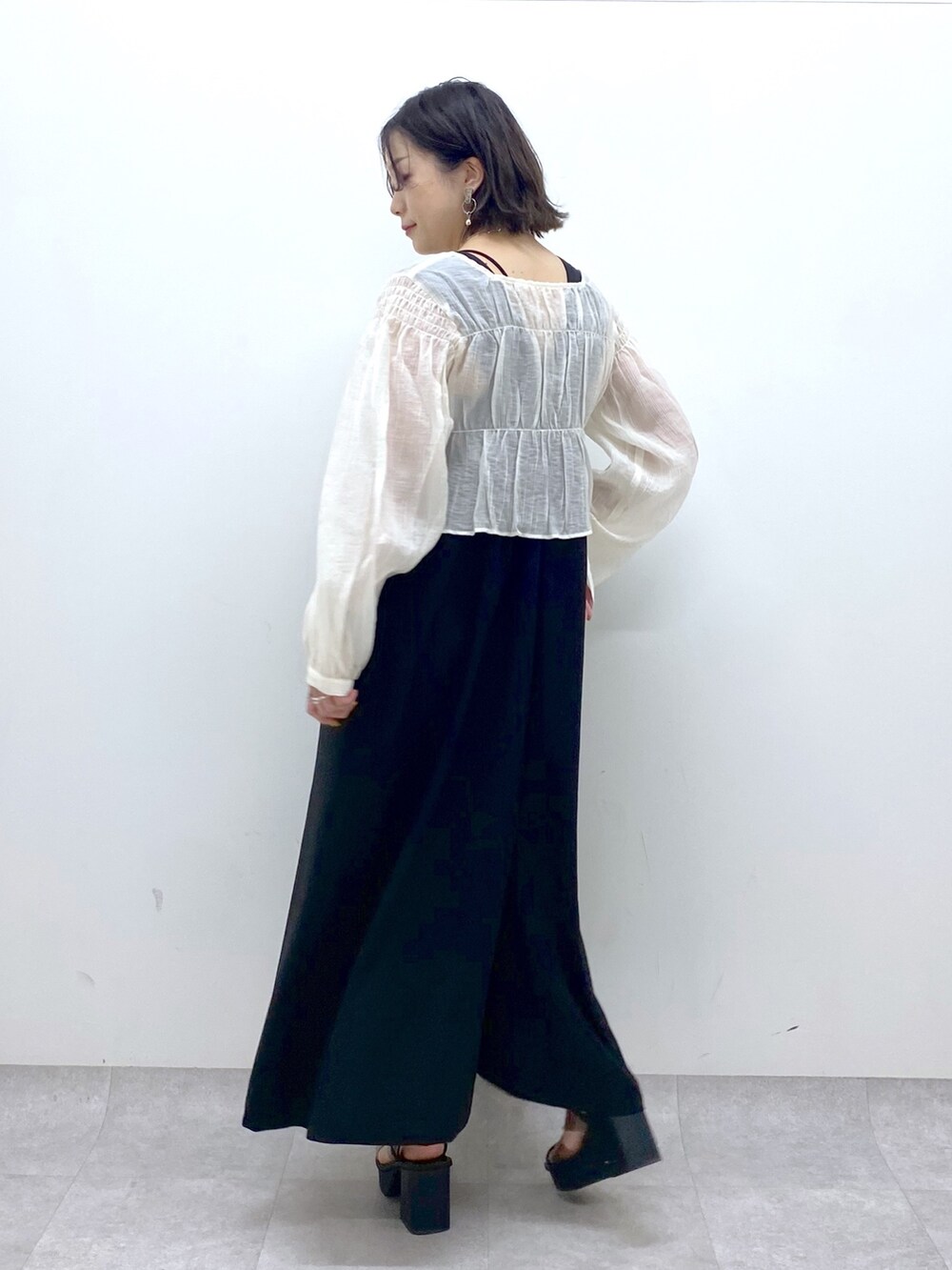 ブラック系のジャンパースカート、ホワイト系のシャツ/ブラウス、その他のサンダルを着用したレディースの夏コーディネートの5枚目の写真