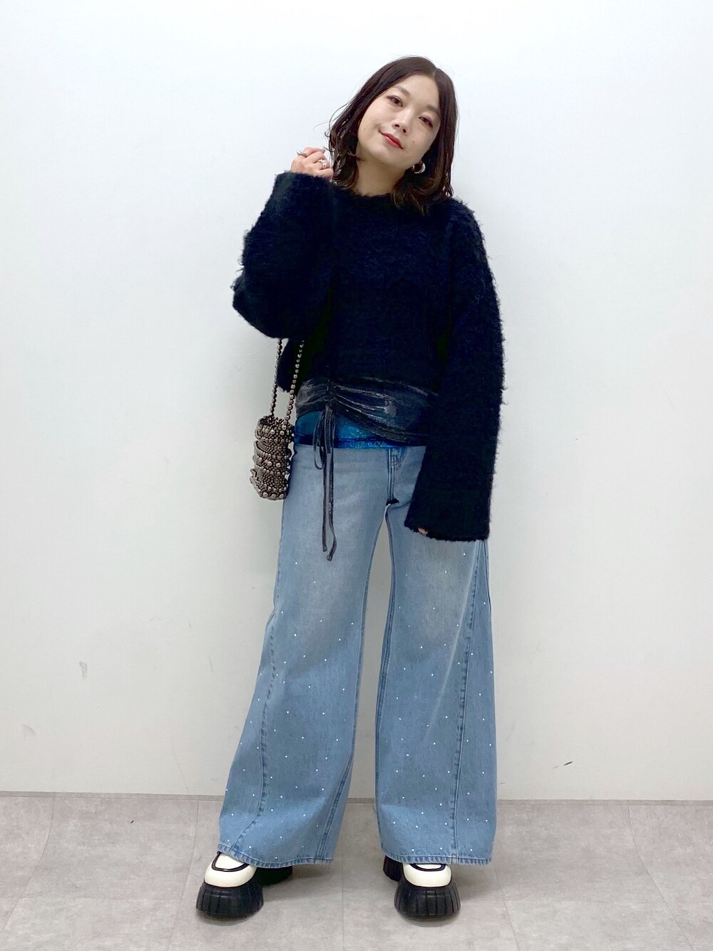 ブラック系のニット/セーター、ブルー系のデニムパンツ、ホワイト系のローファーを着用したレディースの冬コーディネートの9枚目の写真