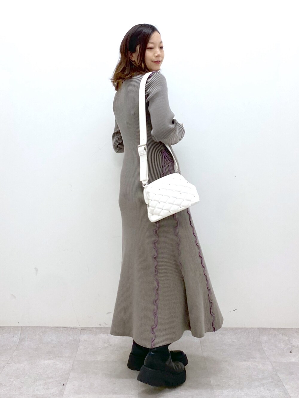 ブラウン系のワンピース、ホワイト系のショルダーバッグ、ブラック系のブーツを着用したレディースの秋コーディネートの3枚目の写真