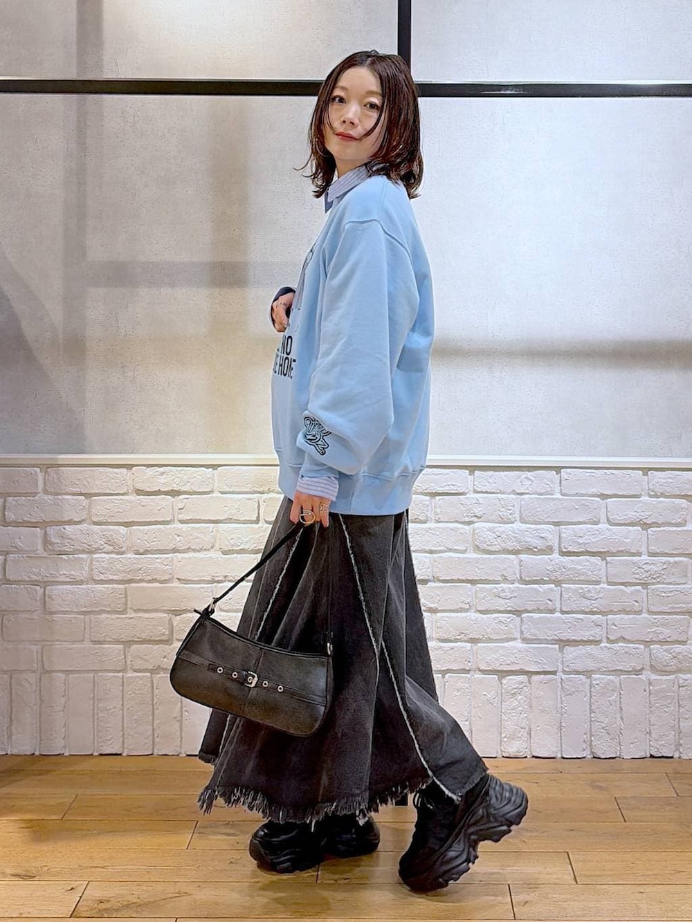 ブラック系のスニーカー、ブラック系のハンドバッグ、ブラック系のデニムスカートを着用したレディースの春コーディネートの5枚目の写真