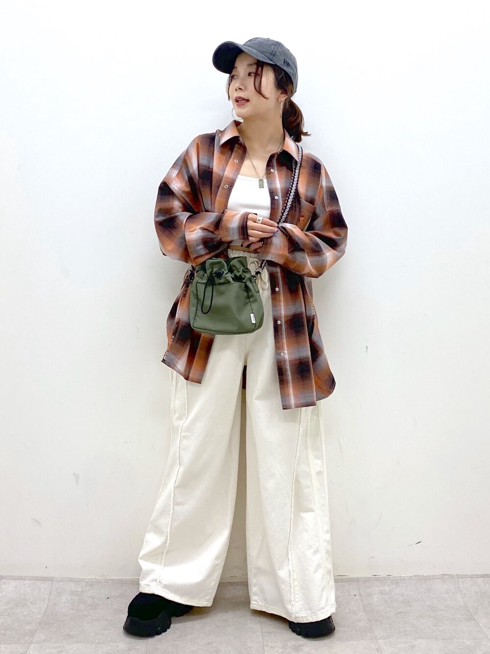 ホワイト系のデニムパンツ、ブラック系のスニーカー、グリーン系のショルダーバッグを着用したレディースの夏コーディネートの4枚目の写真