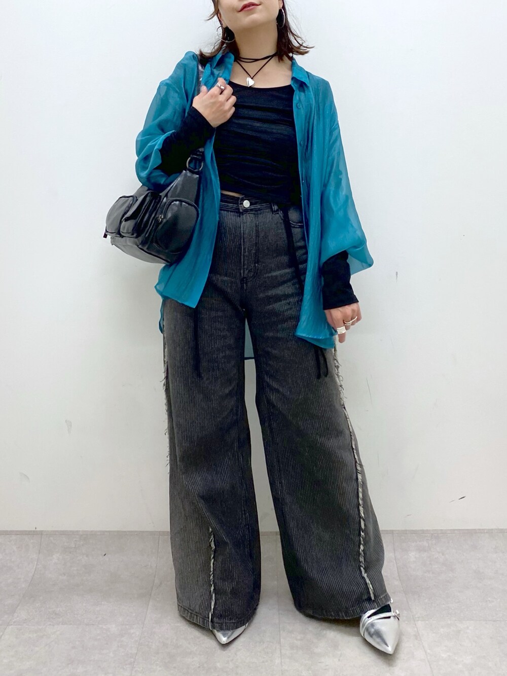 シルバー系のパンプス、ブラック系のデニムパンツ、ブラック系のショルダーバッグを着用したレディースの夏コーディネートの3枚目の写真
