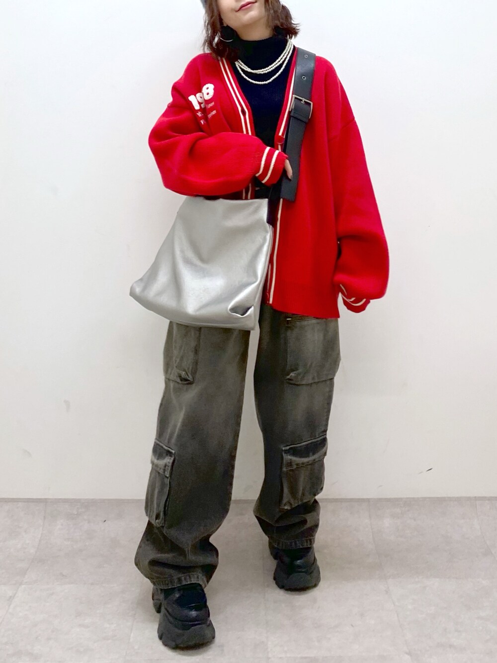 ブラック系のデニムパンツ、ブラック系のブーツ、シルバー系のトートバッグを着用したレディースの秋コーディネートの3枚目の写真