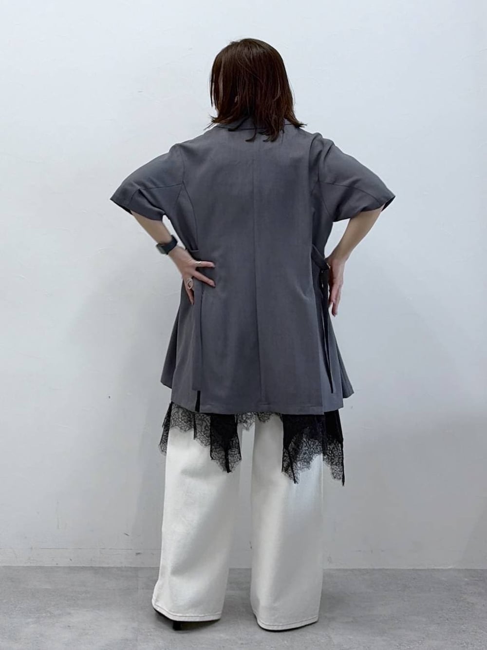 ホワイト系のスラックス、ブラック系のチュニック、ブラック系のサンダルを着用したレディースの春コーディネートの6枚目の写真