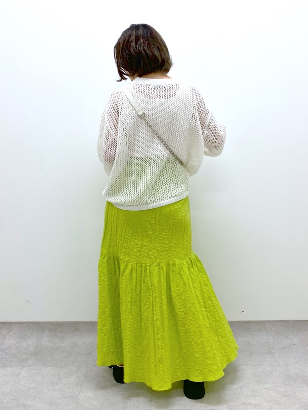 イエロー系のスカート、ホワイト系のバッグ、ホワイト系のトップスを着用したレディースの春コーディネートの3枚目の写真