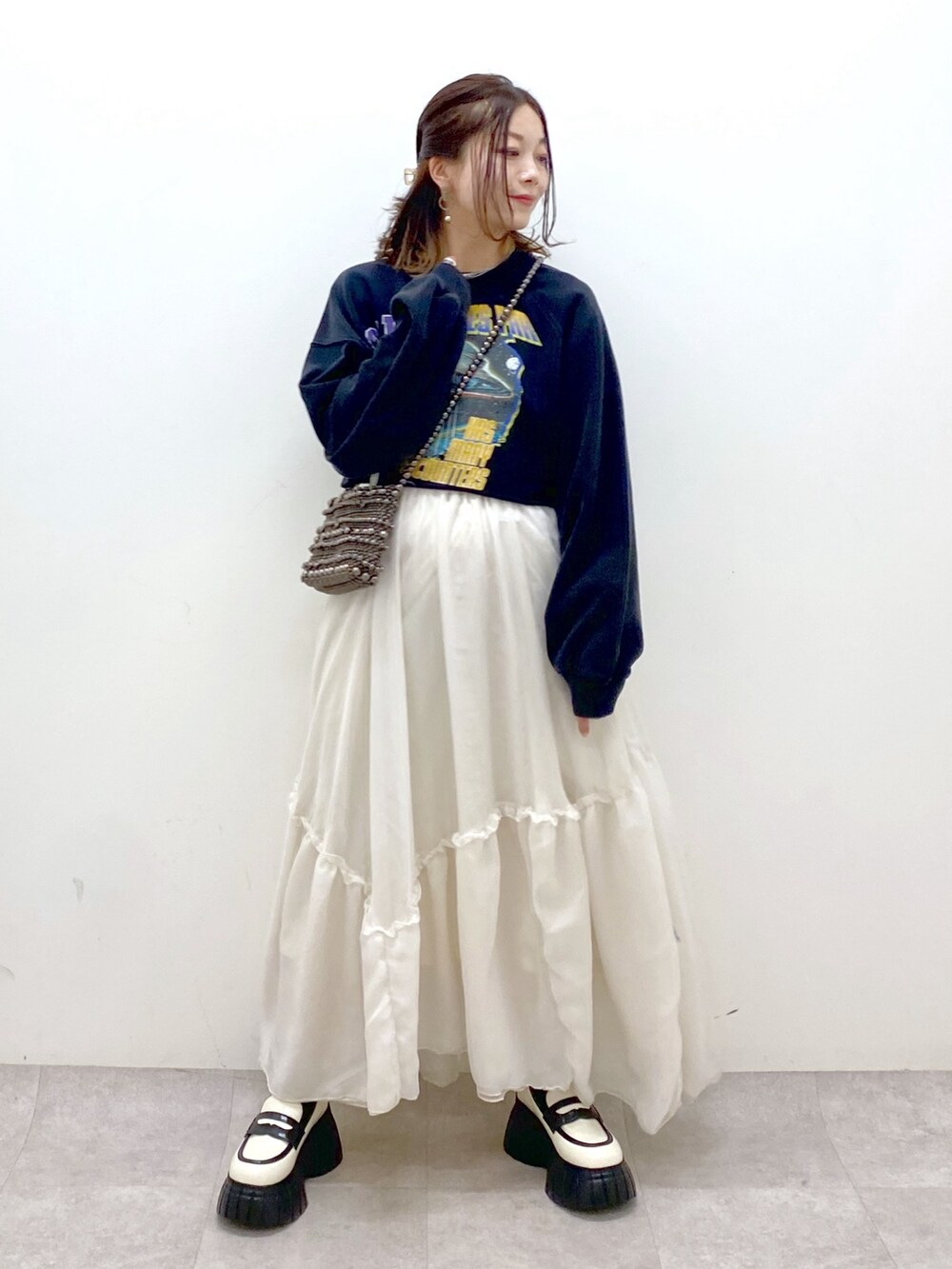 ブラック系のスウェット、ブラック系のショルダーバッグ、ホワイト系のスカートを着用したレディースの冬コーディネートの4枚目の写真