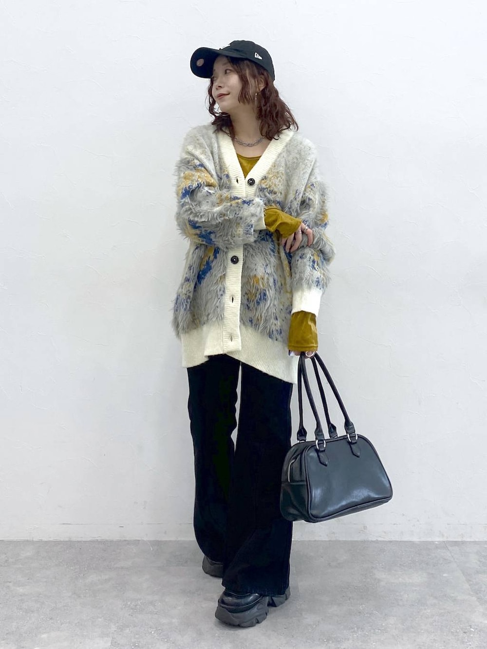 ブラック系のブーツ、ブラック系のボストンバッグ、ホワイト系のカーディガン/ボレロを着用したレディースの秋コーディネートの5枚目の写真