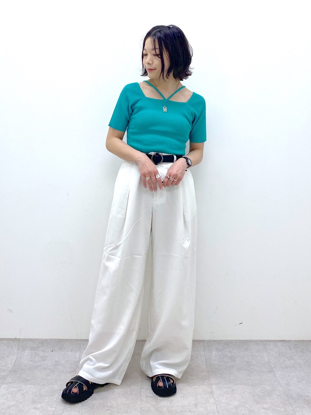 ホワイト系のパンツ、ブラック系のサンダル、ホワイト系のトップスを着用したレディースの春コーディネートの5枚目の写真