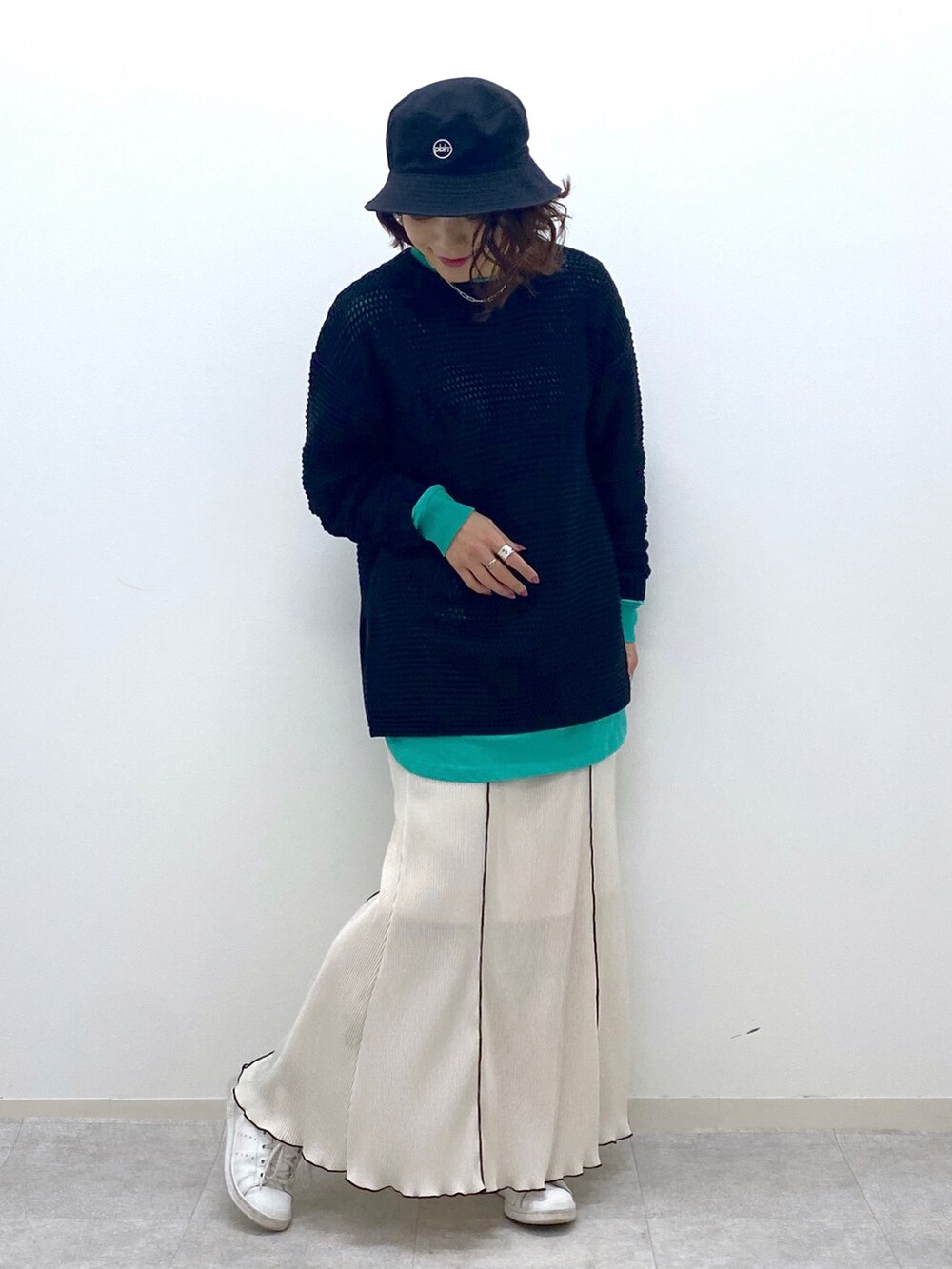 ブラック系のニット/セーター、グリーン系のTシャツ/カットソー、ホワイト系のスカートを着用したレディースの春コーディネートの4枚目の写真