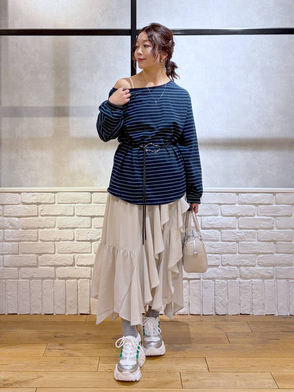 ホワイト系のスニーカー、ベージュ系のスカート、ブラック系のナイロンジャケットを着用したレディースの冬コーディネートの4枚目の写真